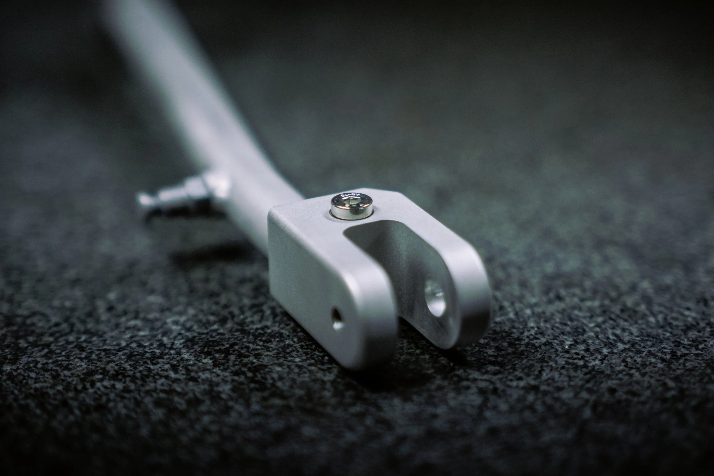 Close-up of a metallic bicycle fork placed on a dark textured surface.