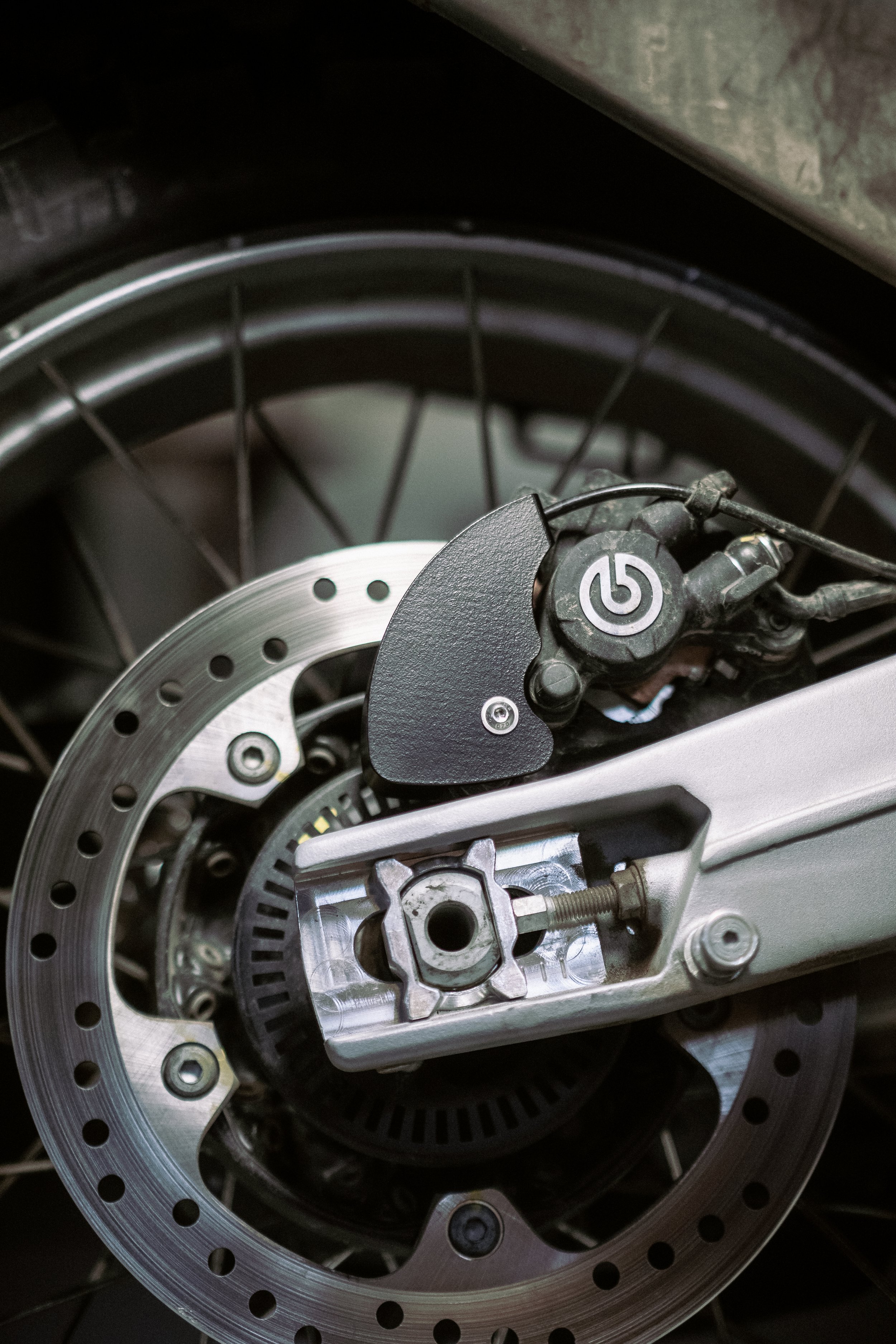 Close-up of Aprilia Tuareg 660 rear disc brake, including the brake disc, caliper, and surrounding components.