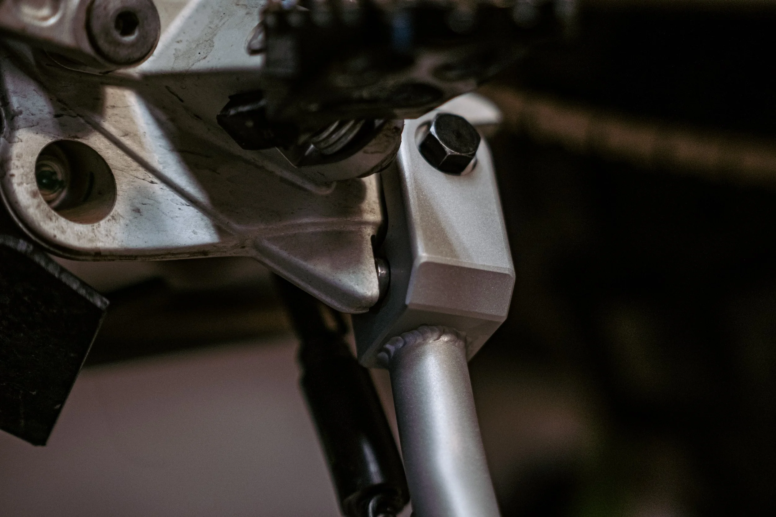 Close-up of motorcycle engine components, showing metallic screws, bolts, and parts of the frame.