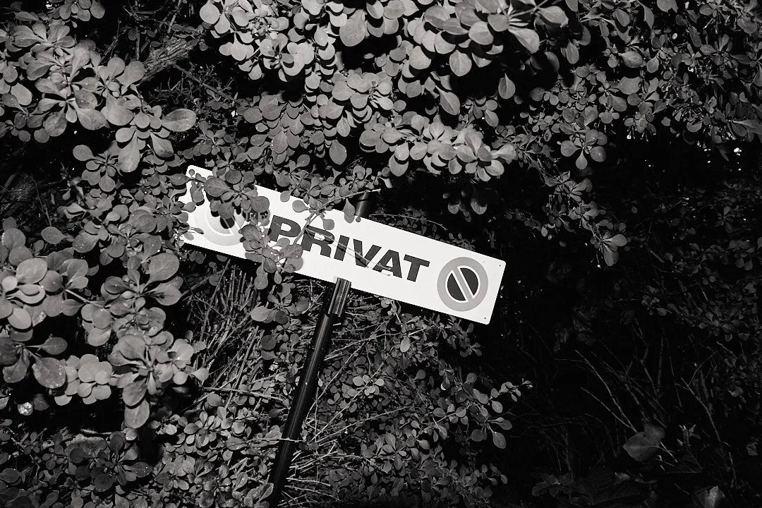 A street sign with the word 'Privat' on it, partially obscured by foliage.