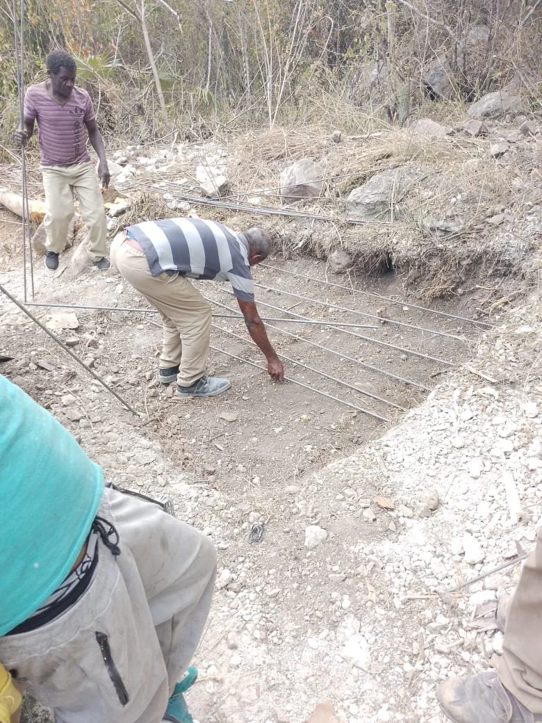 Men arranging steel rods at a construction site in a rural area