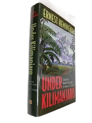 A hardcover book titled 'Under Kilimanjaro' by Ernest Hemingway, featuring an illustrated cover with tropical landscape and snow-capped mountain in the background.