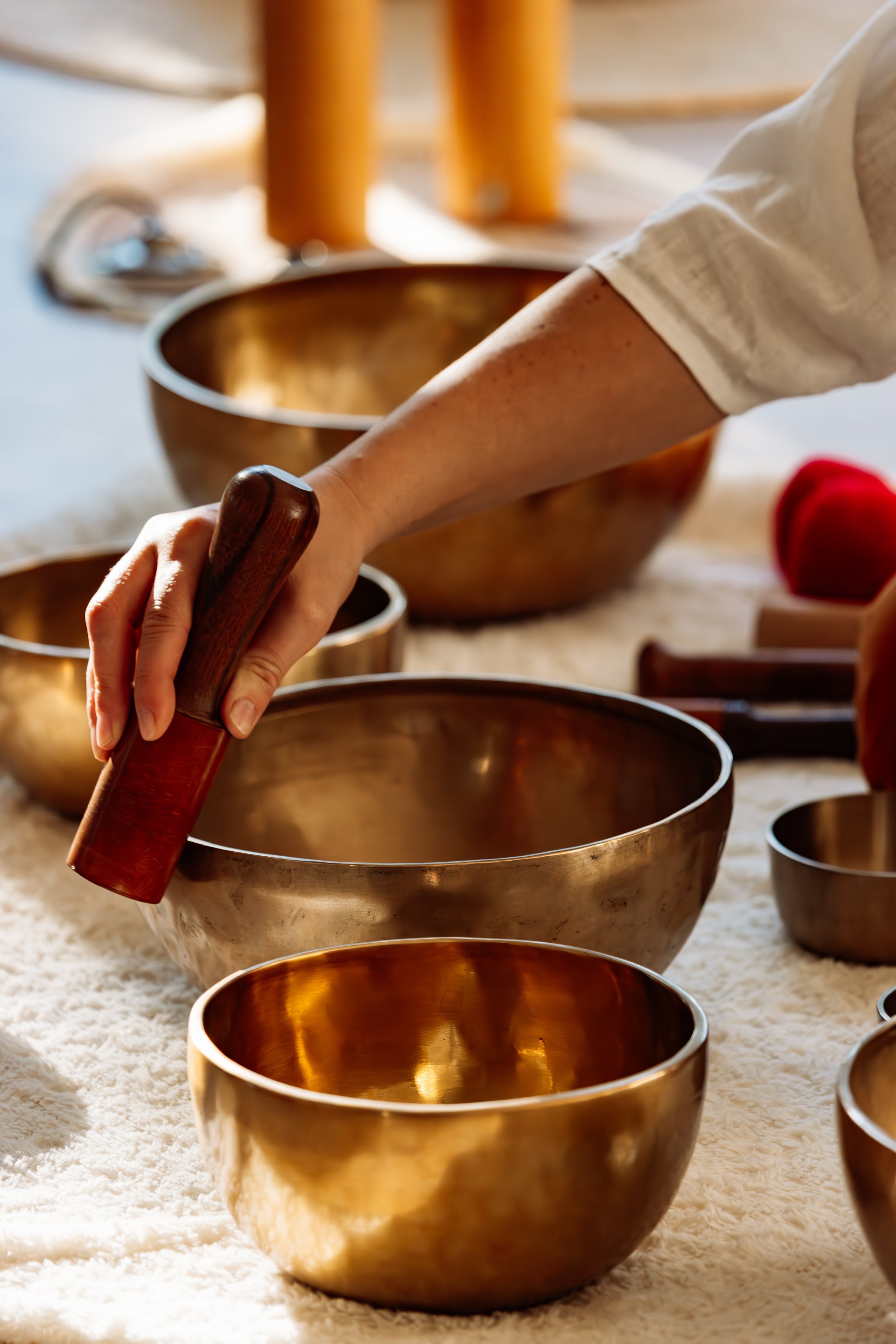 Une personne utilisant un bâton pour jouer un bol en métal sur une surface recouverte de tissu.