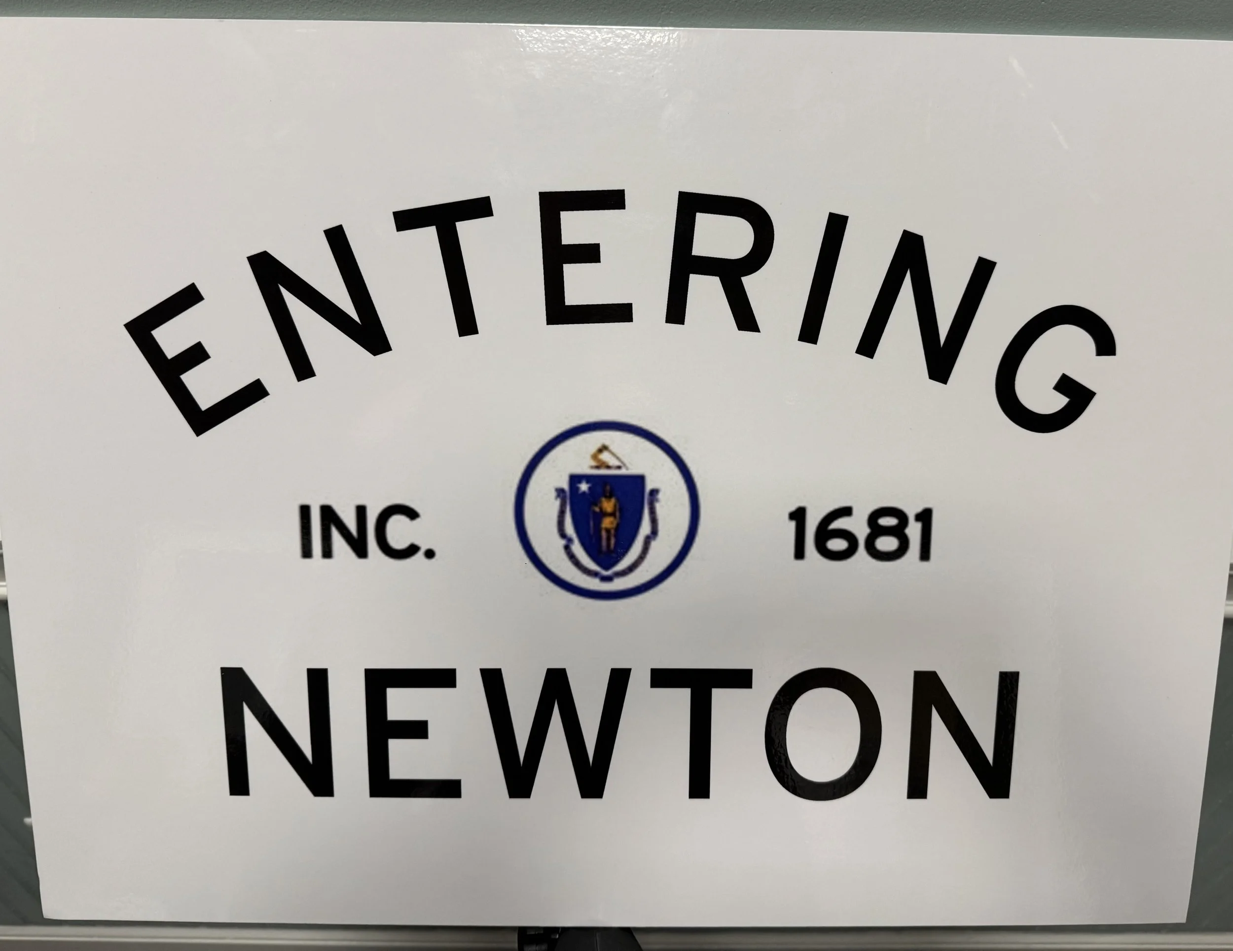 A white sign with black letters that says "Entering Newton"