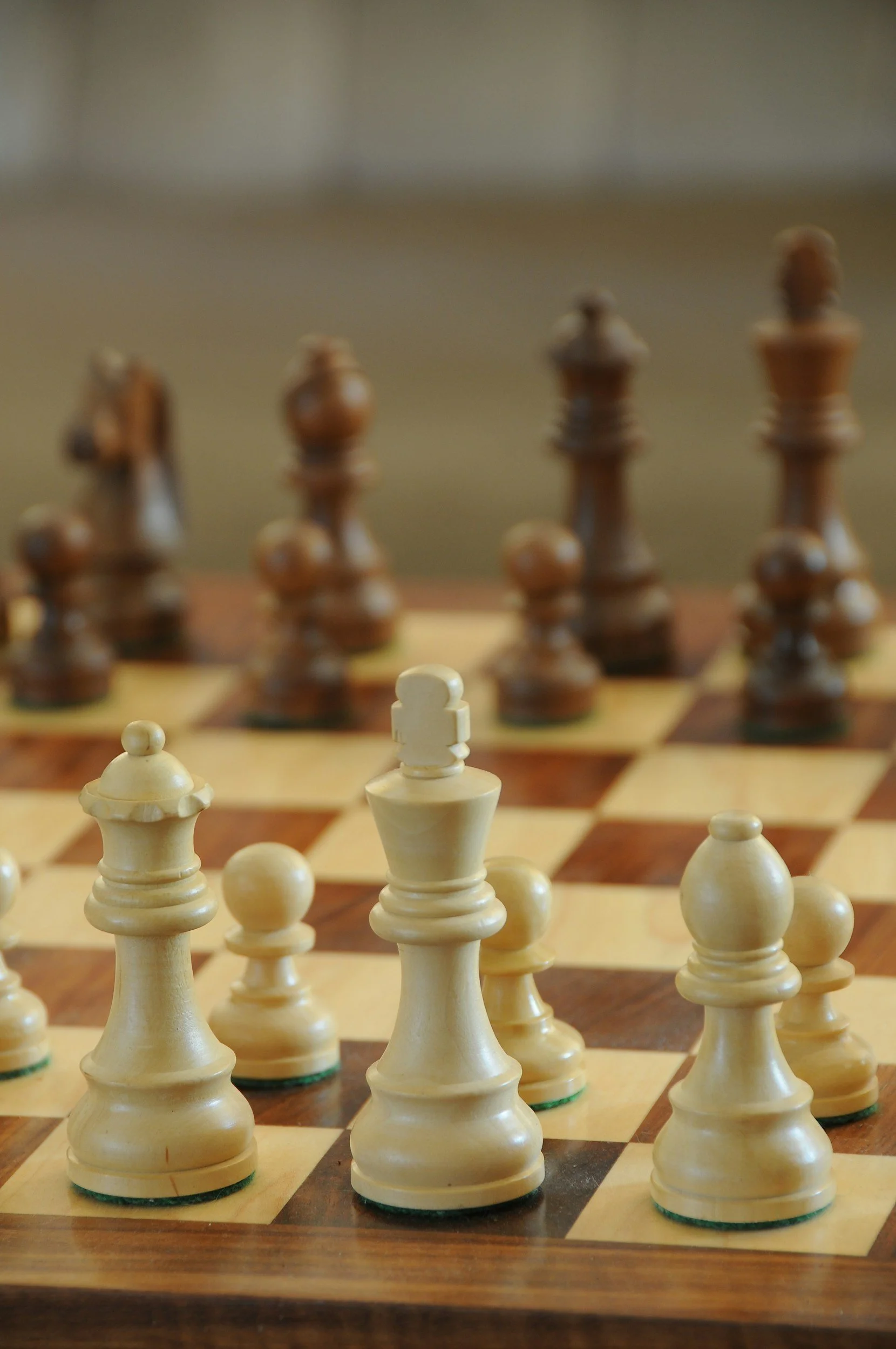 Close-up of a chessboard with white and brown chess pieces, with focus on the white king, in a game setting.