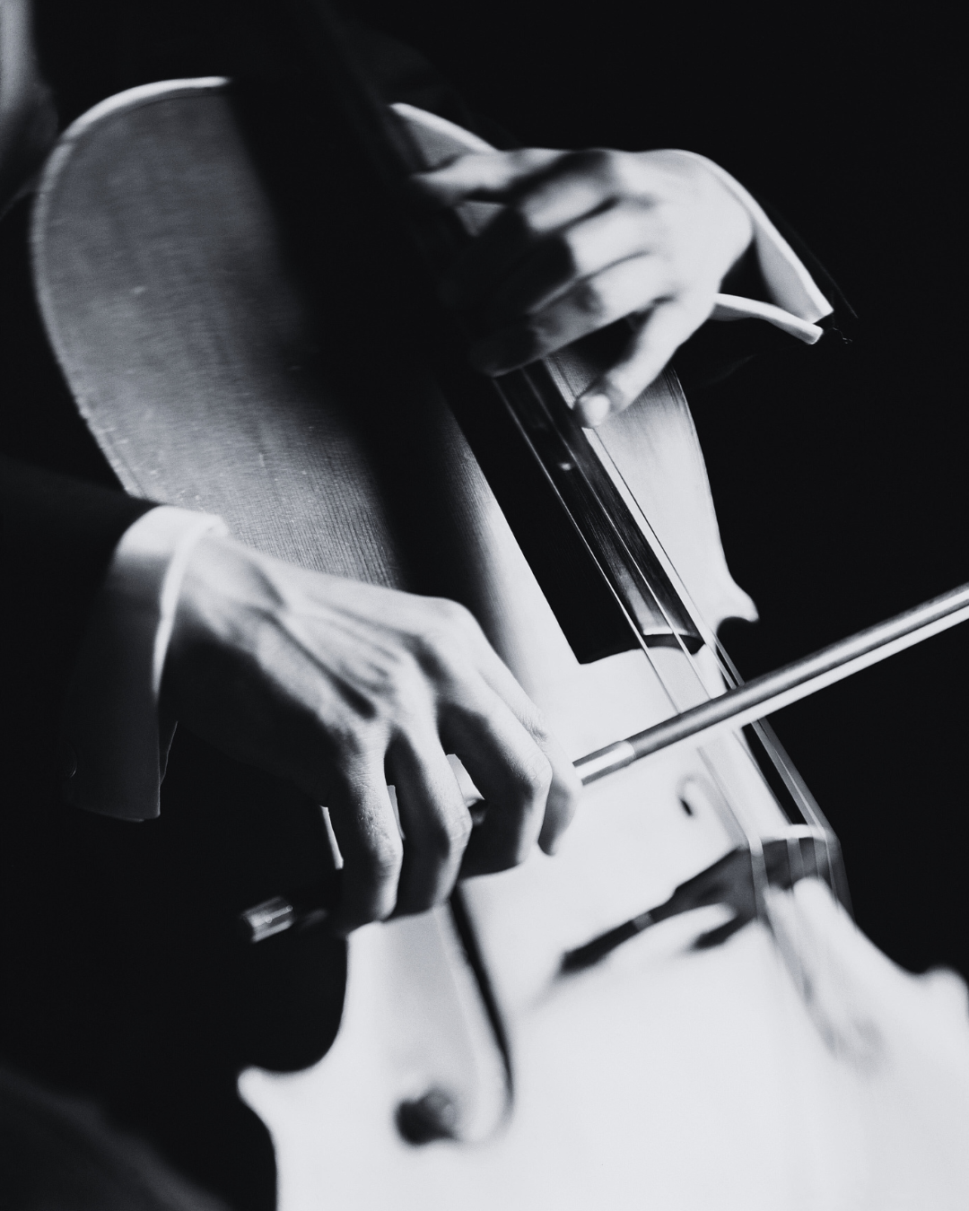 Mano che suona un violoncello in bianco e nero.