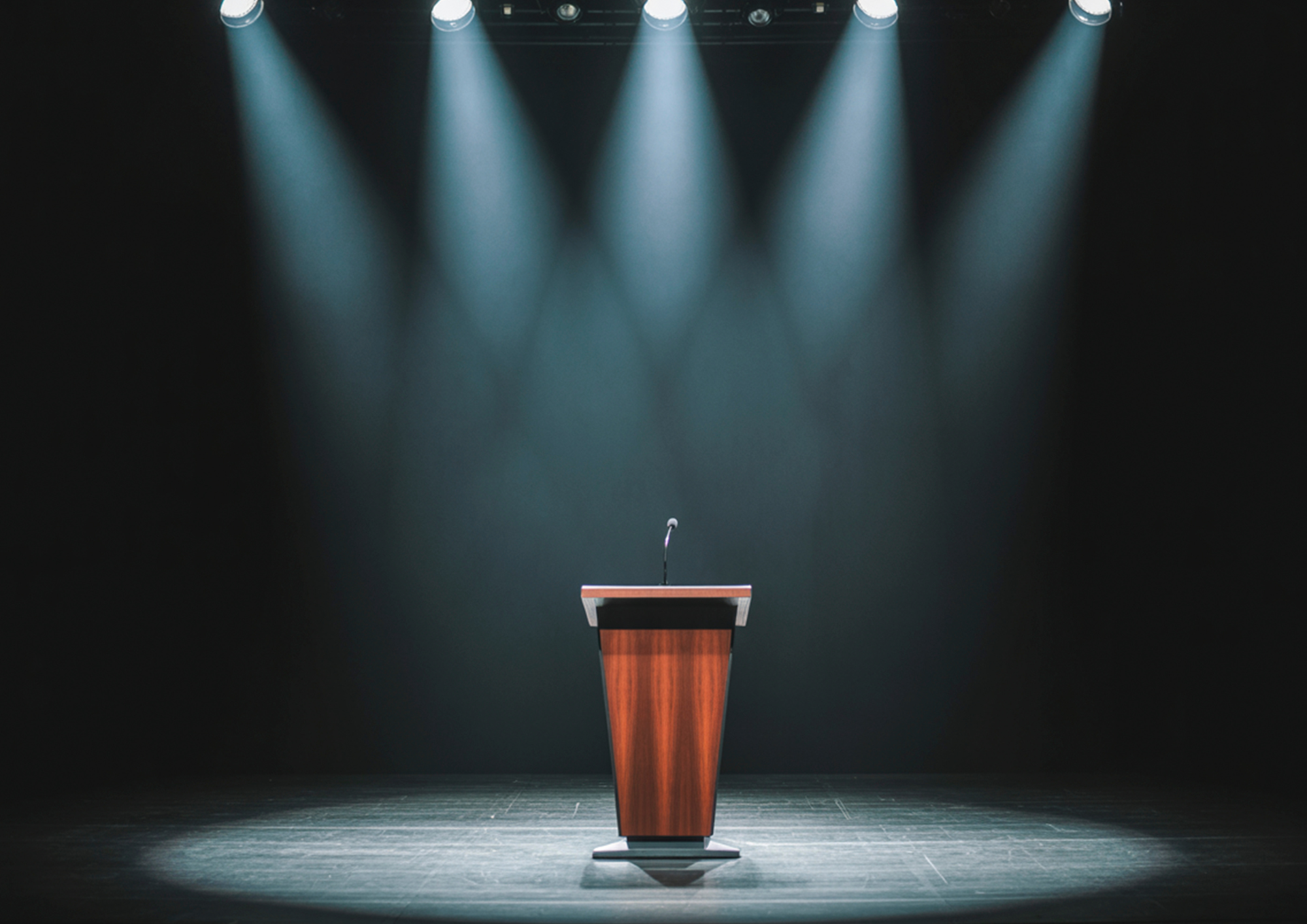 Podio e microfono su un palco vuoto illuminato da luci teatrali