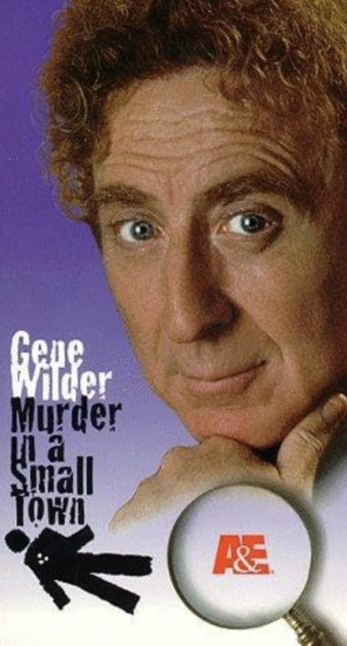 Close-up of a woman with curly red hair looking at the camera with a thoughtful expression, next to a magnifying glass and the title "Gene Wilder Murder in a Small Town."