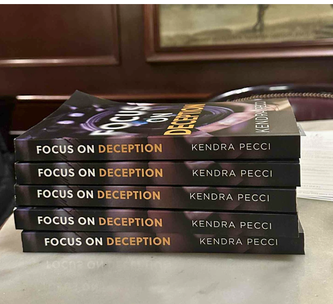 Person writing in a notebook with a pen, on a black surface. Kendra Pecci knew she wanted to write from a very early age, but thought it was just a hobby.