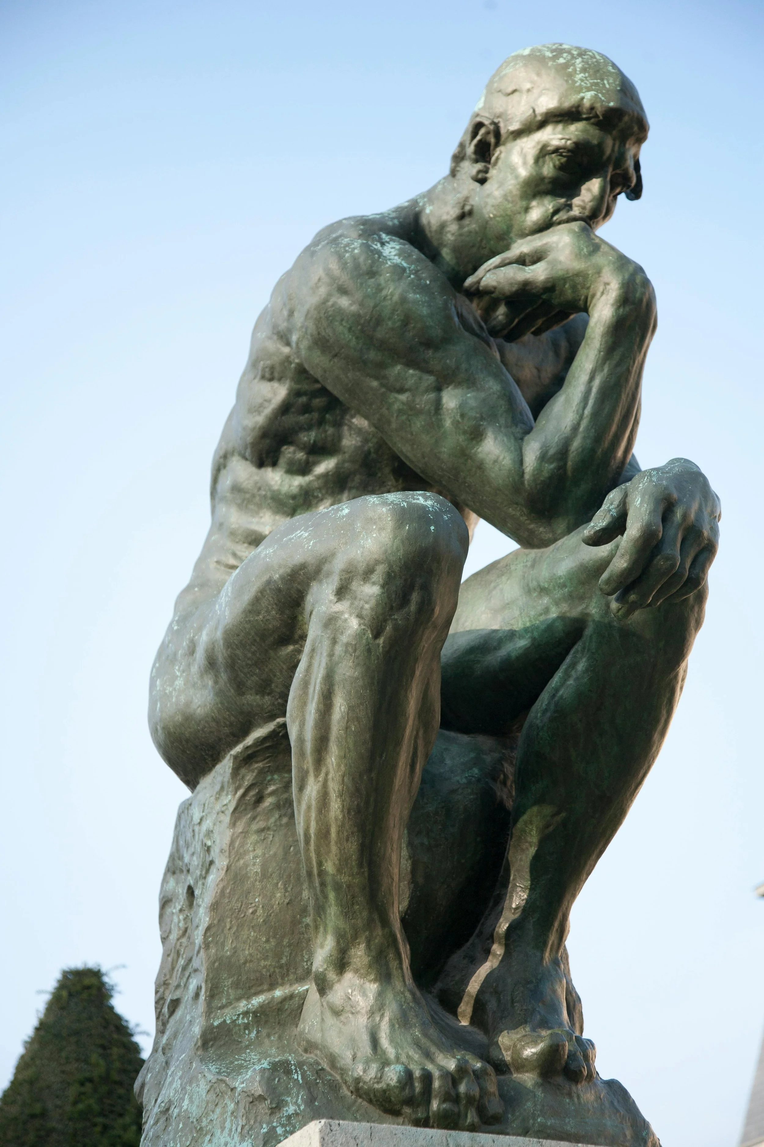 Die Skulptur des Denkers von Rodin vor blauem Himmel als Symbol für Kritisches Denken