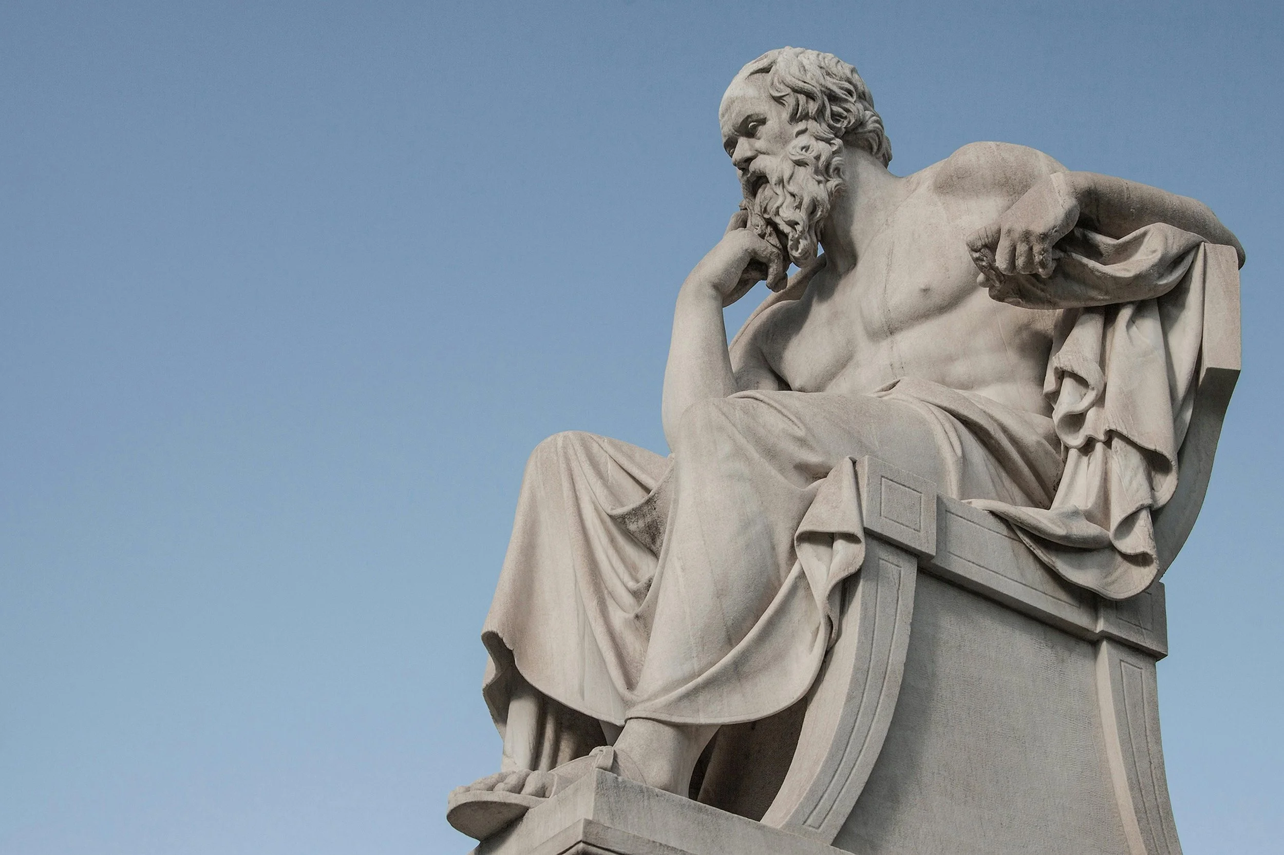 Statue of Socrates seated with his head resting on his hand, depicted in a reflective, contemplative pose.