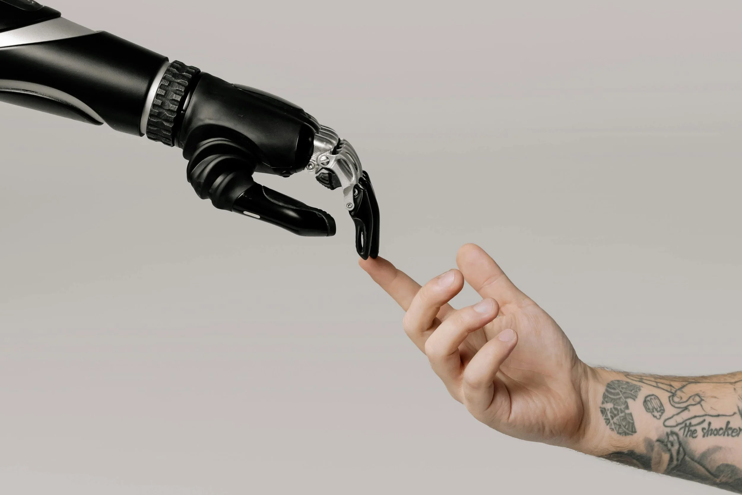 A human hand making contact with a robotic hand, symbolising interaction between humans and artificial intelligence.