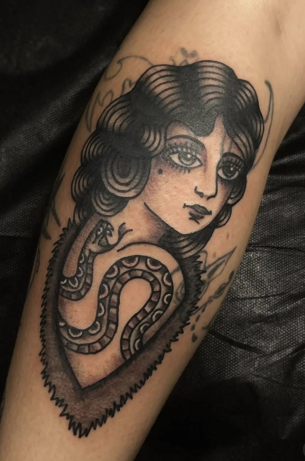 Tattoo of a stylized woman with a snake wrapped around her shoulder.