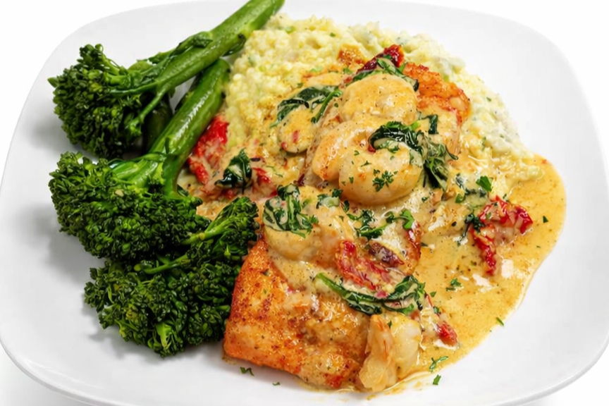 Plate of fish with shrimp in a creamy sauce, served with mashed potatoes and fresh broccoli.
