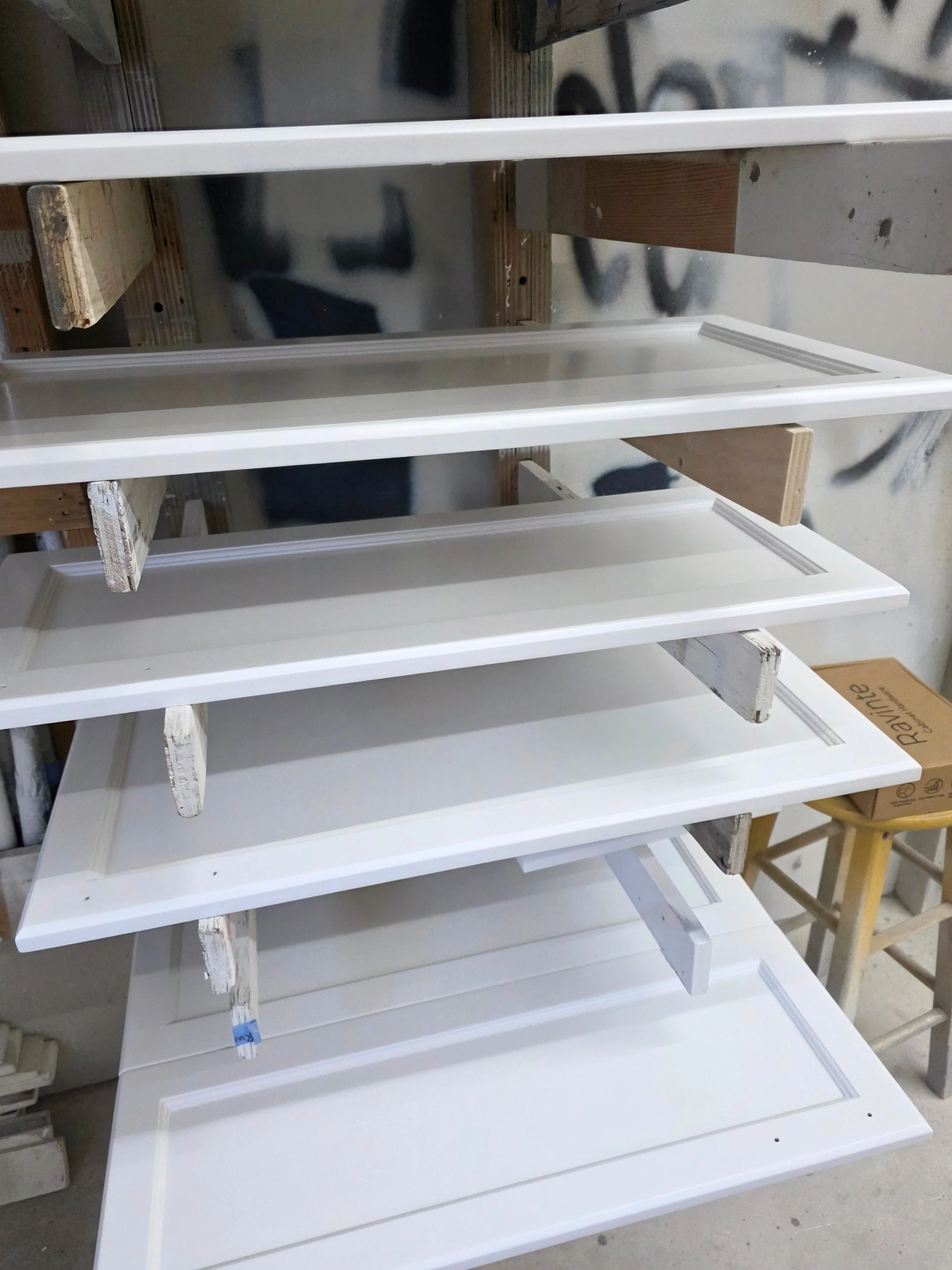 Kitchen cabinet doors being spray-finished in the Final Coat Painting shop for a Canmore refinishing project