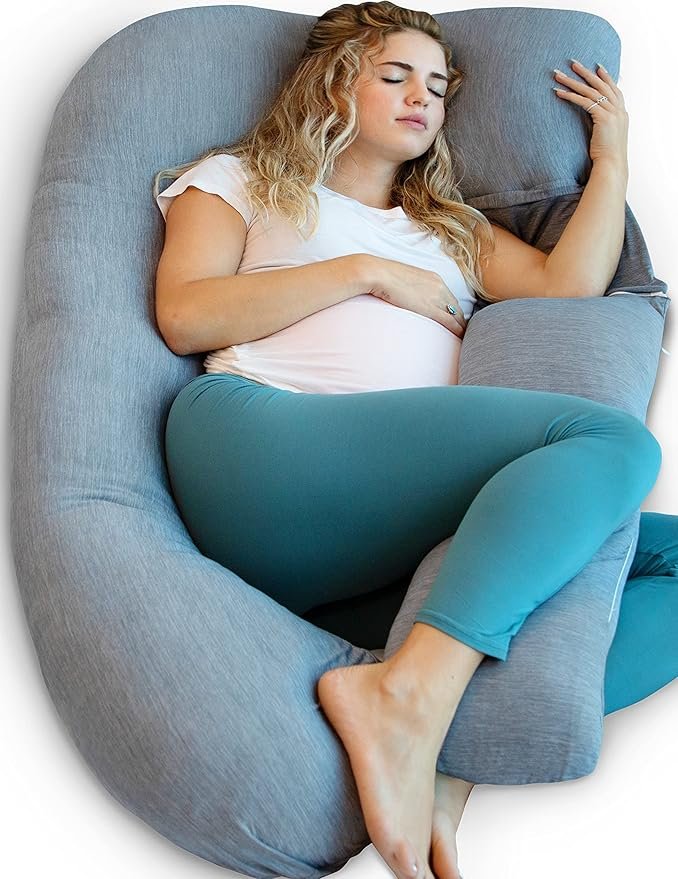 Young woman with curly blonde hair sleeping in a gray cushioned chair, wearing a white t-shirt and teal leggings.