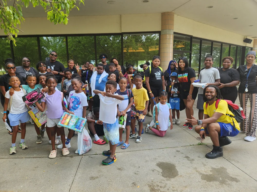 Youth and adults gather outside a building during a group outing.