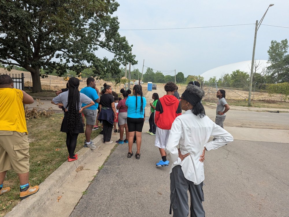 Young people and adults gather outdoors during a youth program outing.