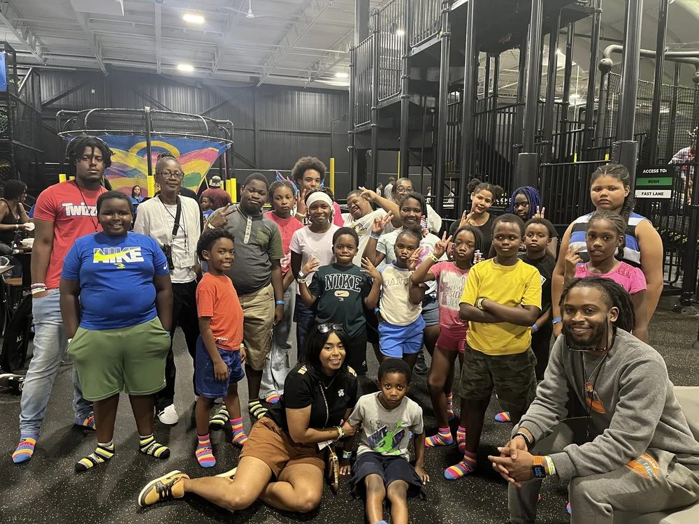 Youth and adults pose together at an indoor recreation venue.