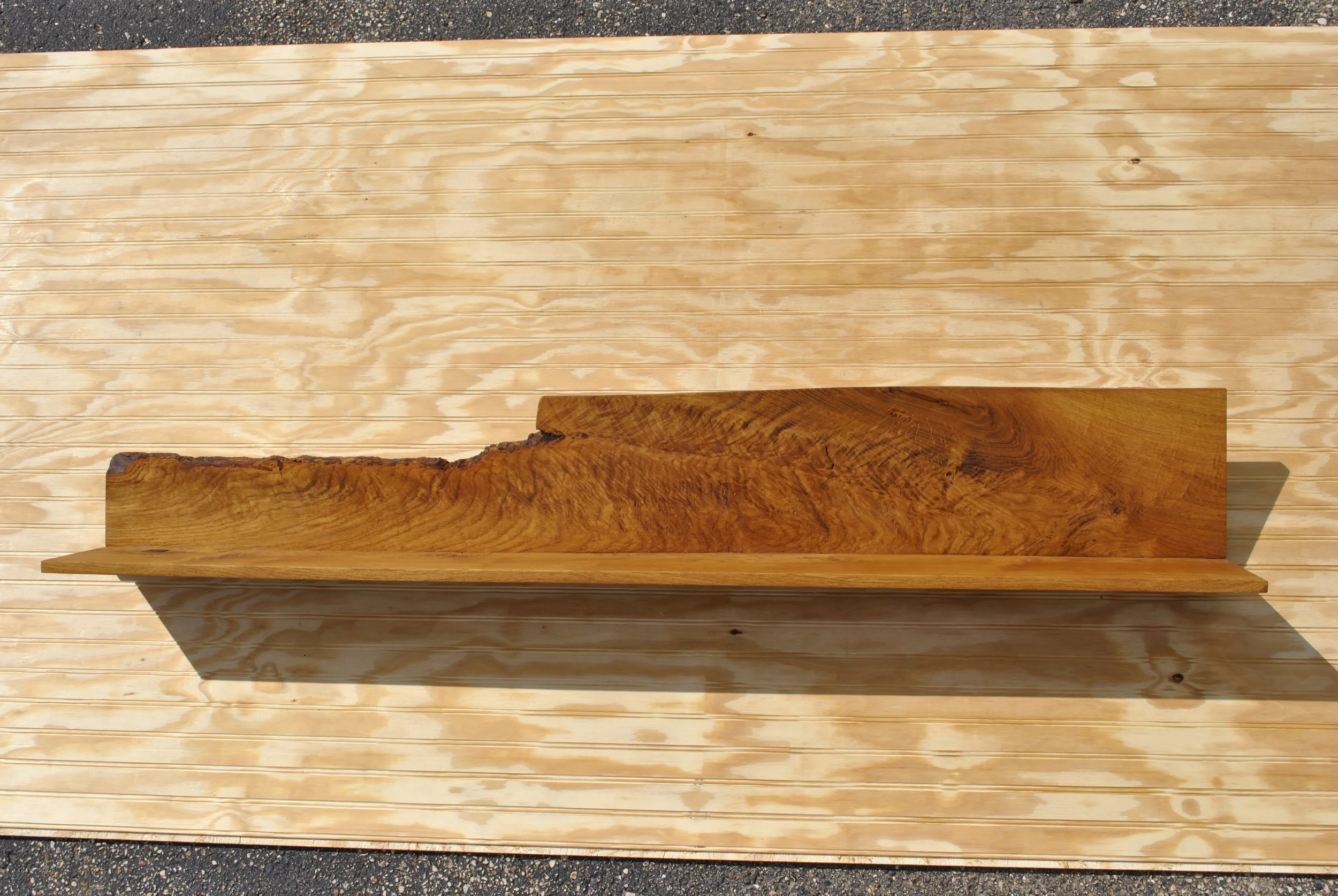 Wooden shelf with a natural edge, mounted on a light-colored wooden wall with horizontal planks.