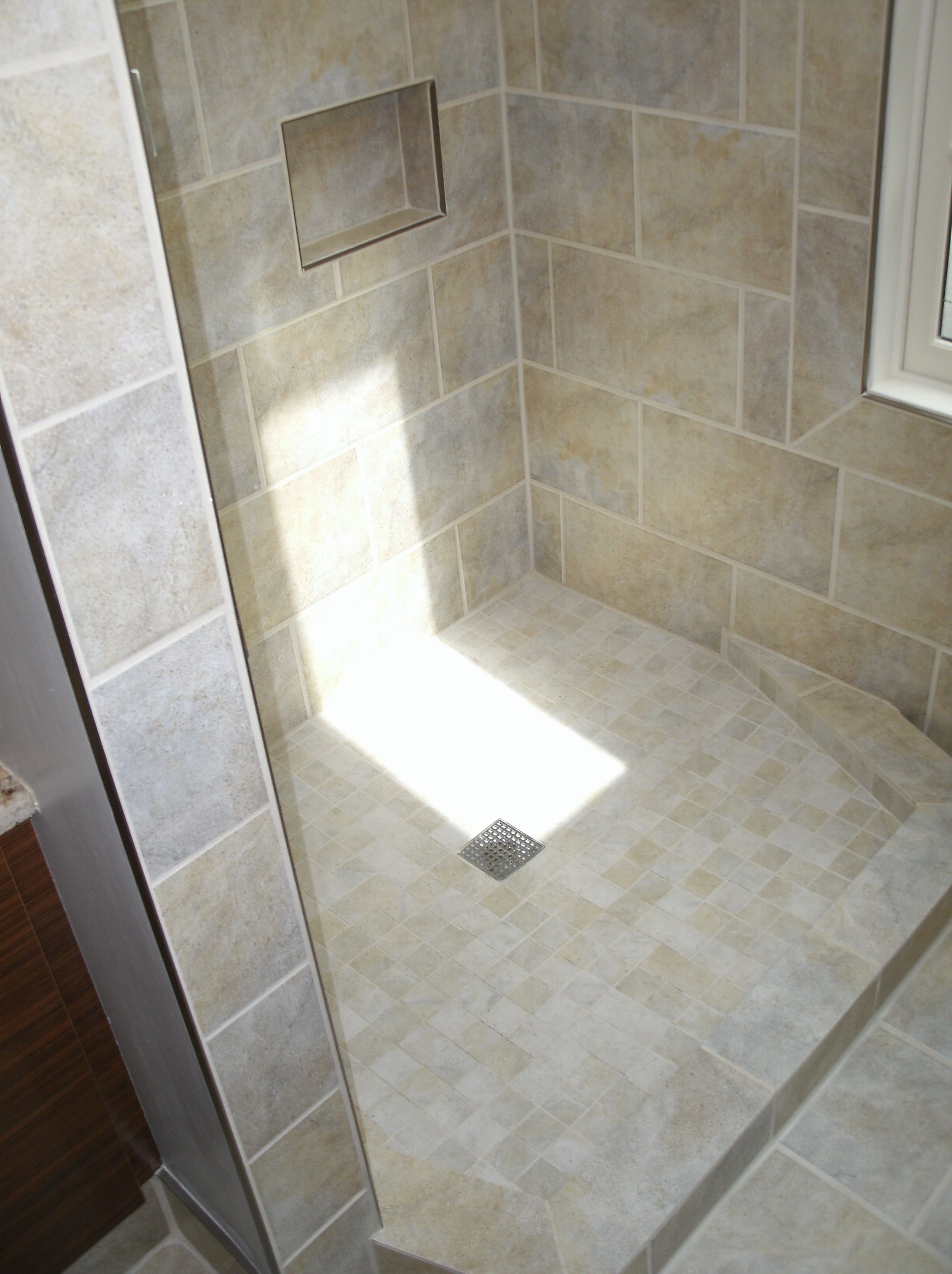 Walk in shower with curb all tiled. Nice skylight light element.