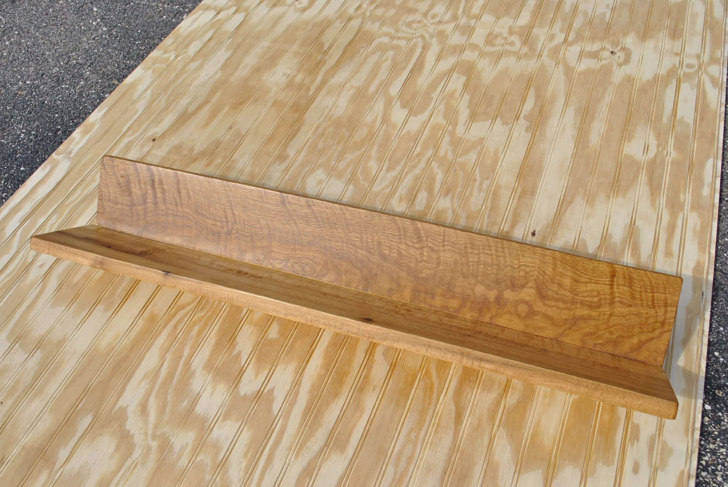 A wooden picture frame on a wooden table floor with a hard surface in the background.