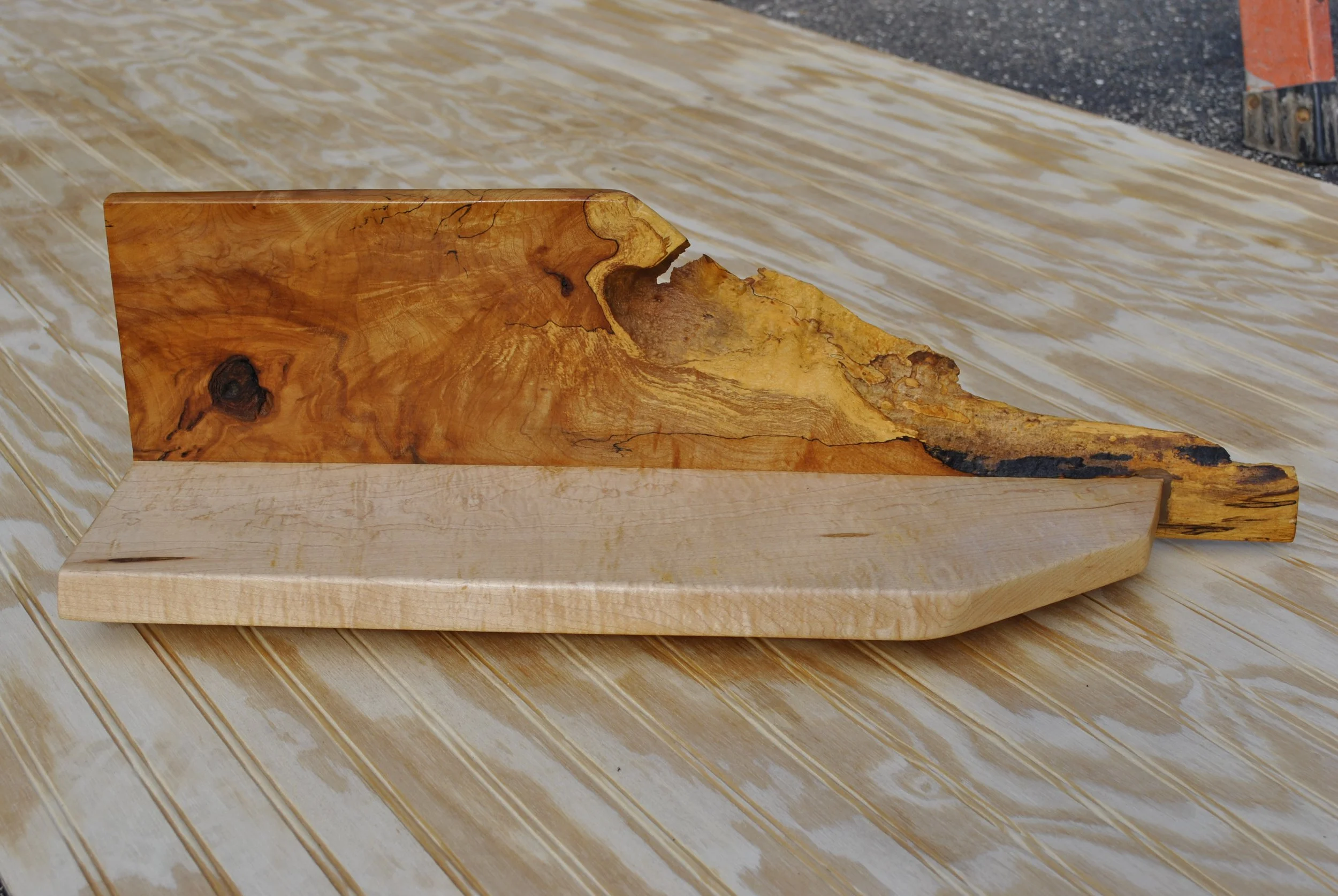A wooden piece with two distinct types of wood, one with a natural and rough surface and the other smoothly finished, placed on a surface covered with plastic sheeting.