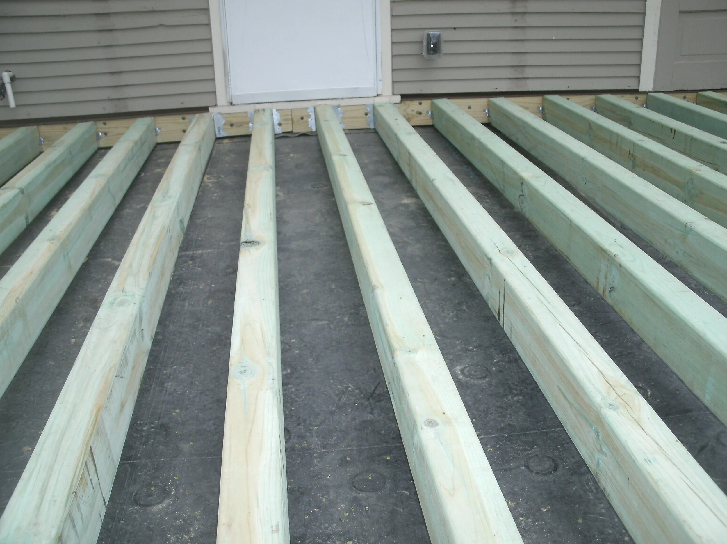 Rubber roof visible beneath joists. Joist suspended over roof, not touching the roof.