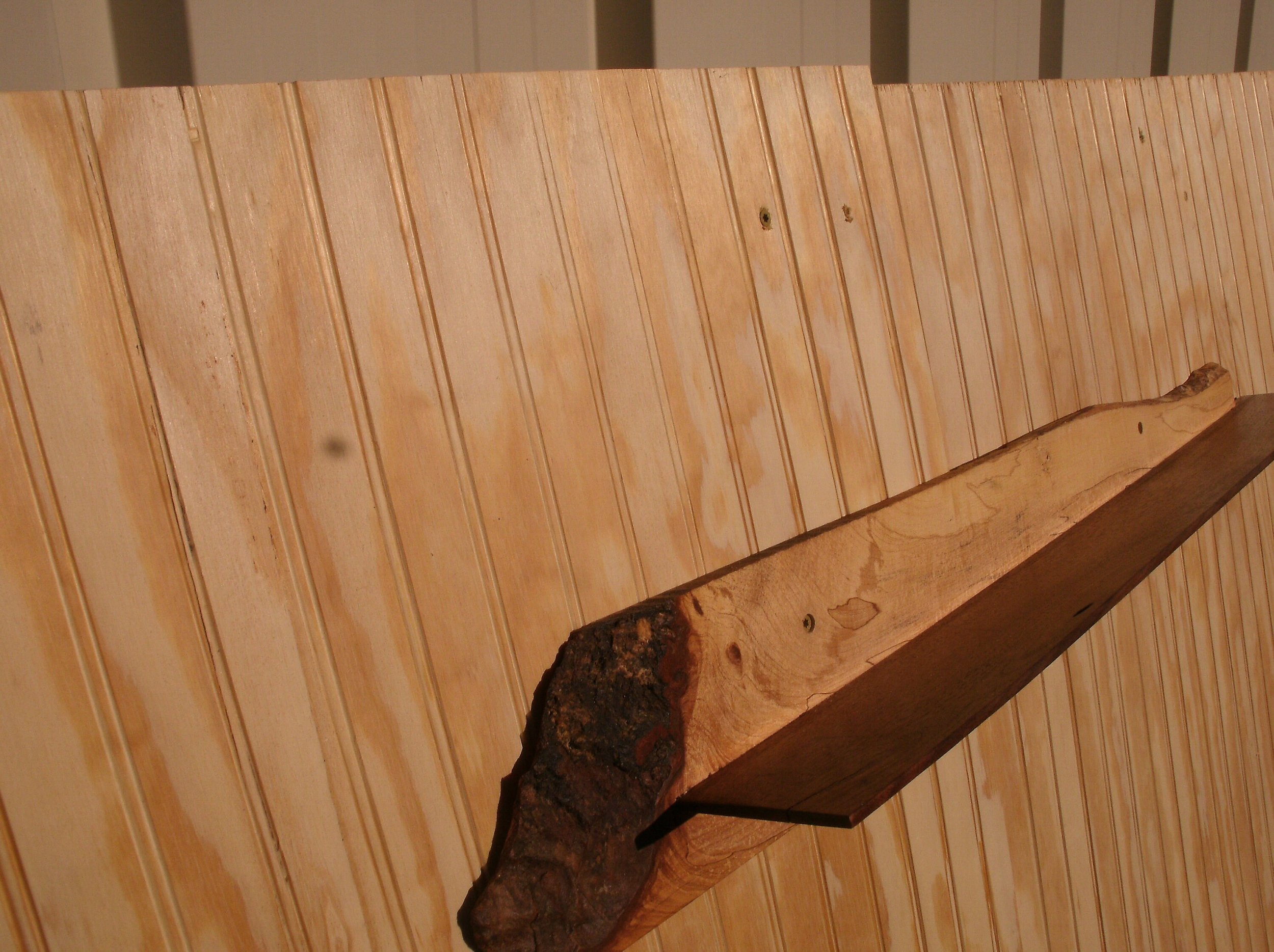 Wooden wall with vertical planks and a wooden shelf protruding from the wall.