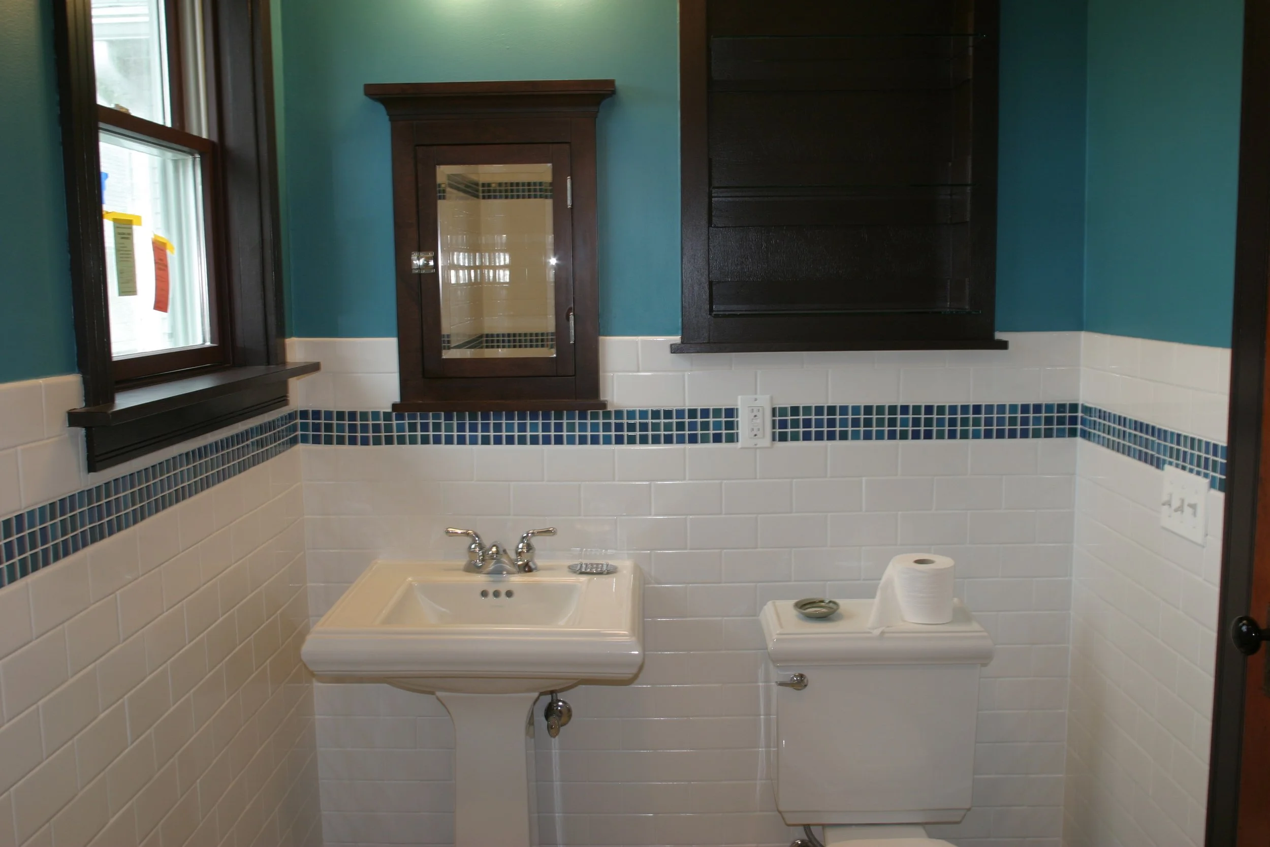 This is the view of the sink and the toilet, and the medicine cabinet and storage shelving.