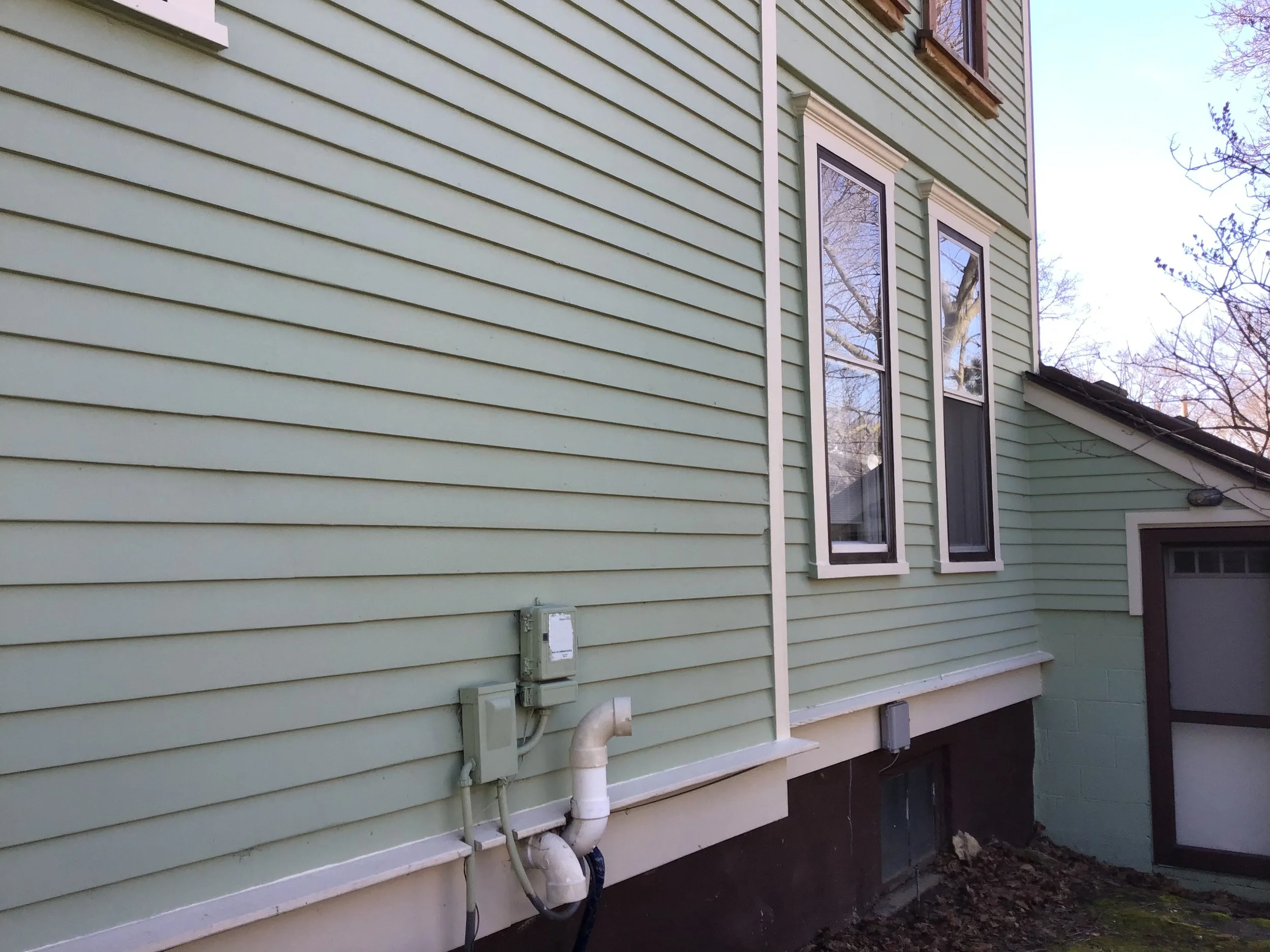 Partial view of replaced stretches of siding, window trim painted.