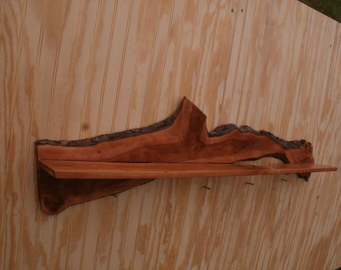 Wooden decorative shelf with natural bark edge mounted on a light-colored wooden wall.
