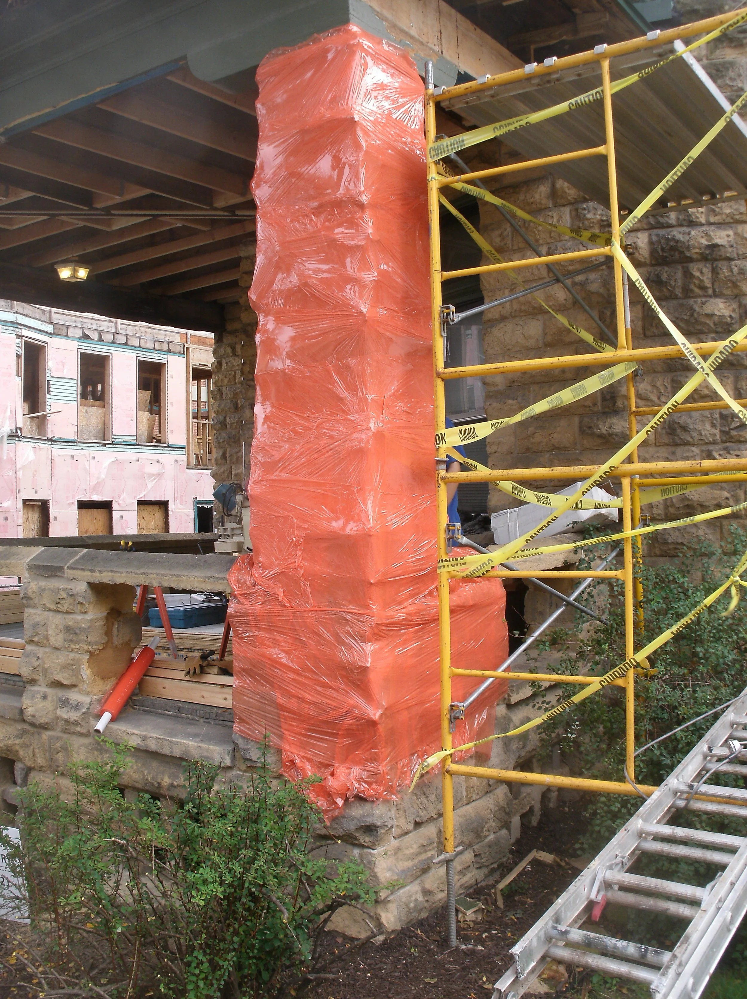 Stone pier wrapped with multiple thicknesses of cling wrap for partial protection.
