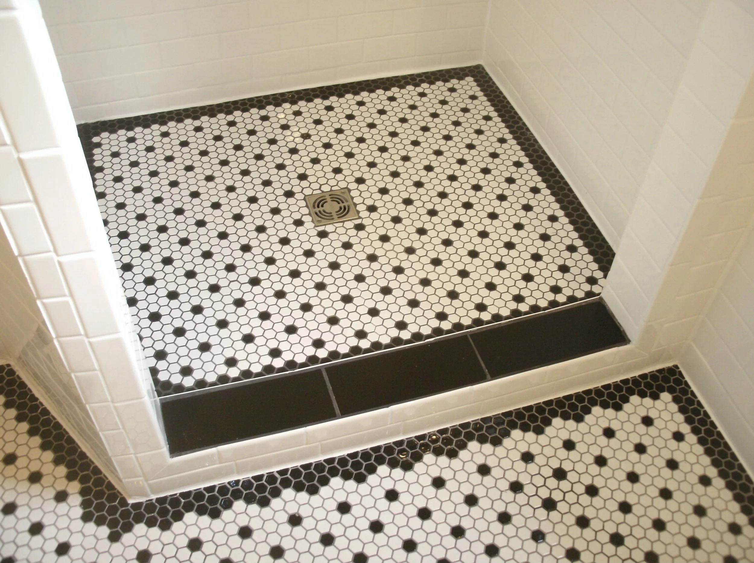 A view of the shower, curb, and tile floor