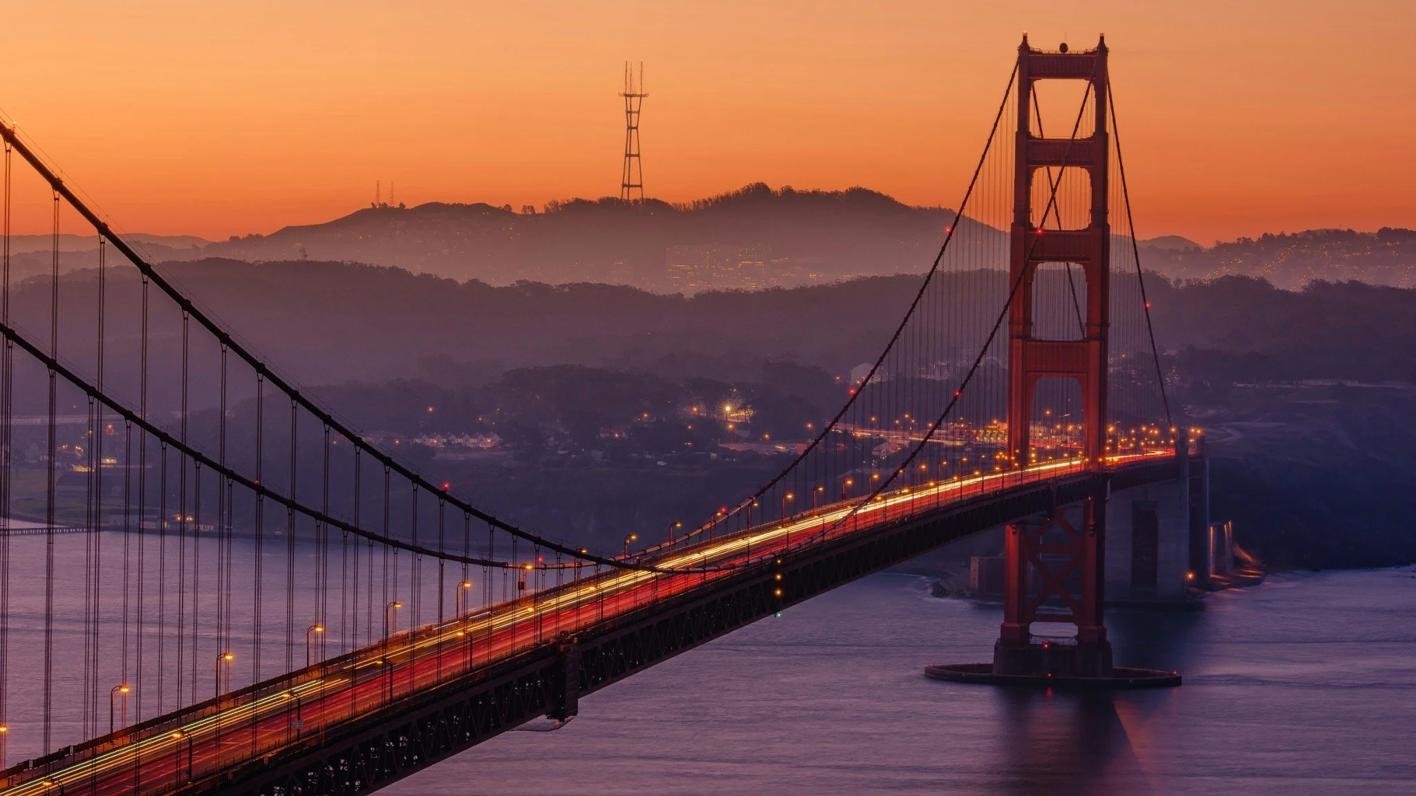 Golden Gate Bridge at sunset with cityscape in the background.