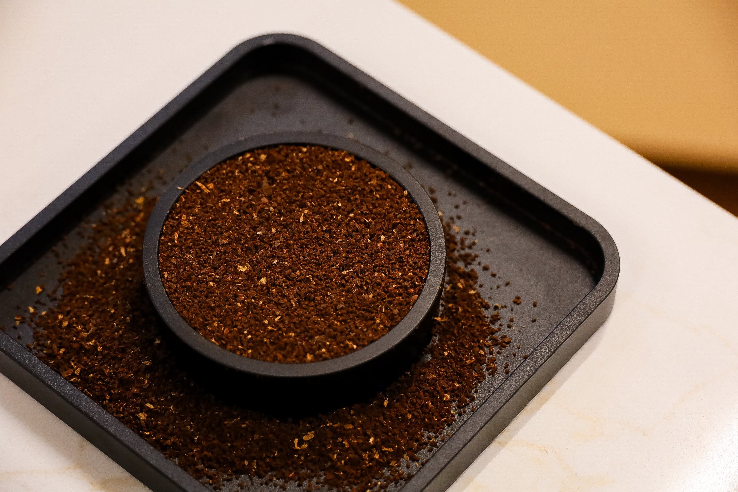 Ground coffee in a black container on a table.
