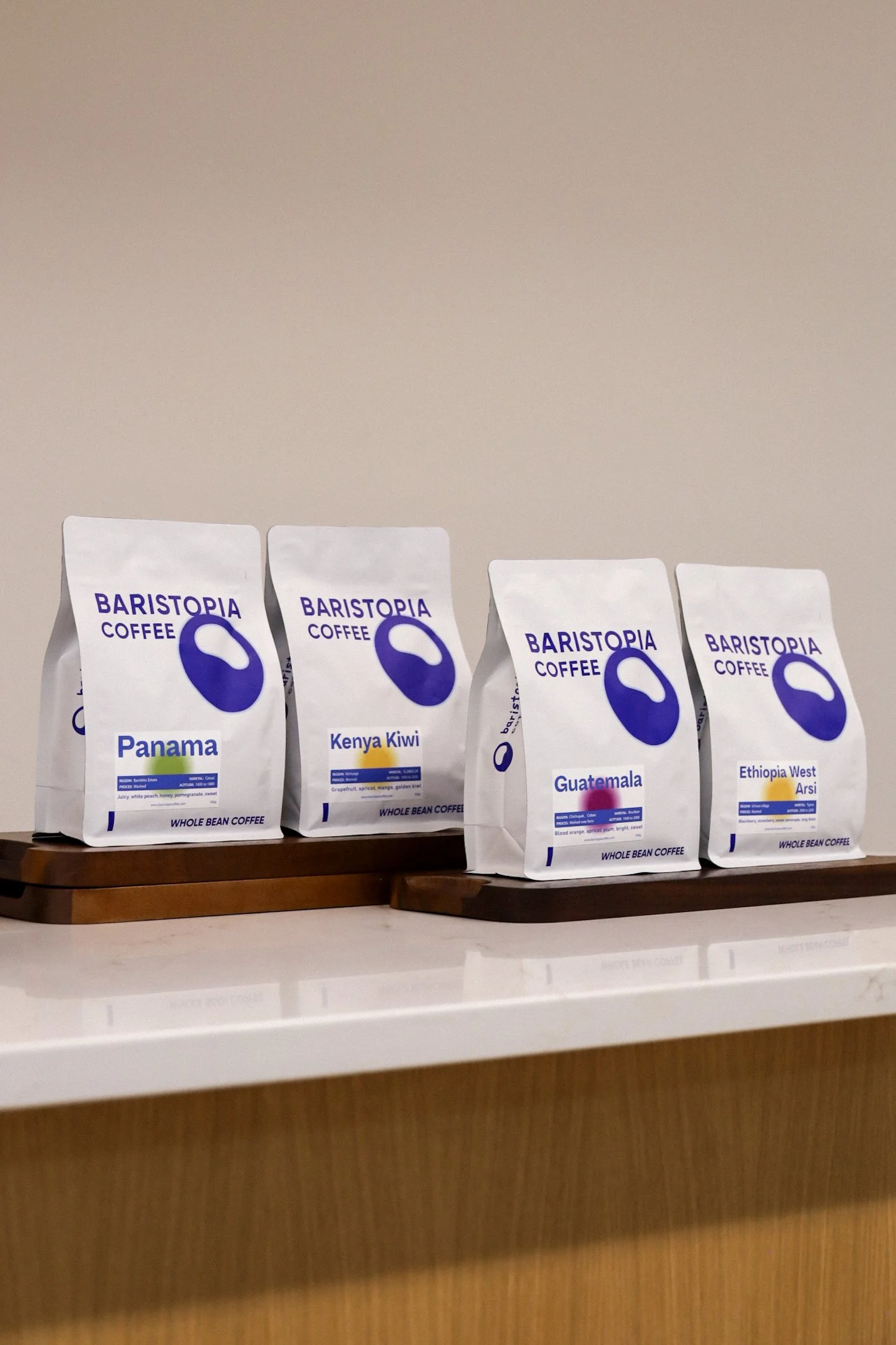 Four bags of Baristopia Coffee on a counter, labeled Panama, Kenya Kiwi, Guatemala, and Ethiopia West Arsi.