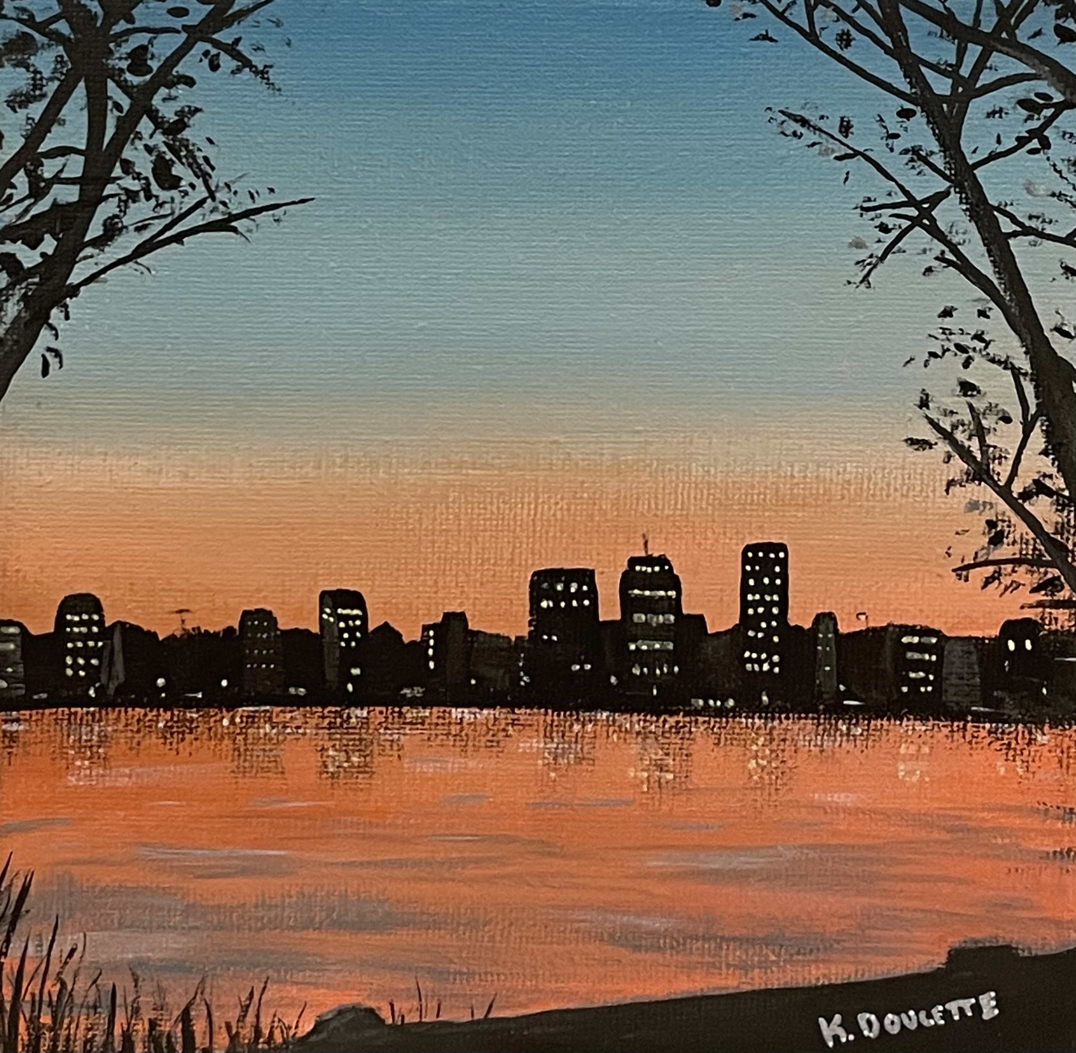 City skyline silhouette against a sunset, reflected in a body of water, with trees framing the scene.