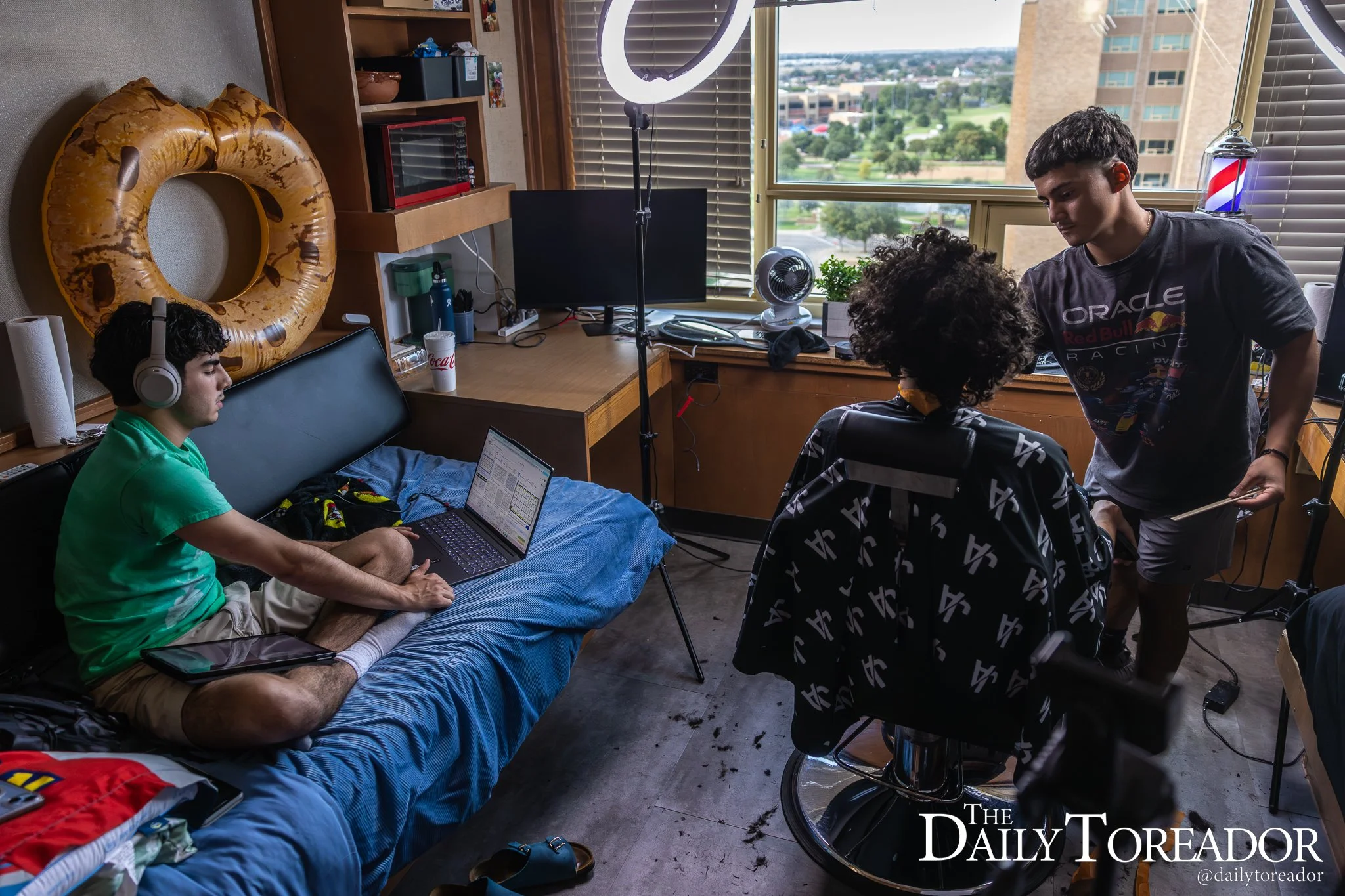 Texas Tech freshman business management major Juan Aguirre, right, cuts a client’s hair while his roommate completes his homework inside Coleman Hall, in Lubbock. Aguirre is known online as the “TTU Barber” where he posts the haircuts he gives studen