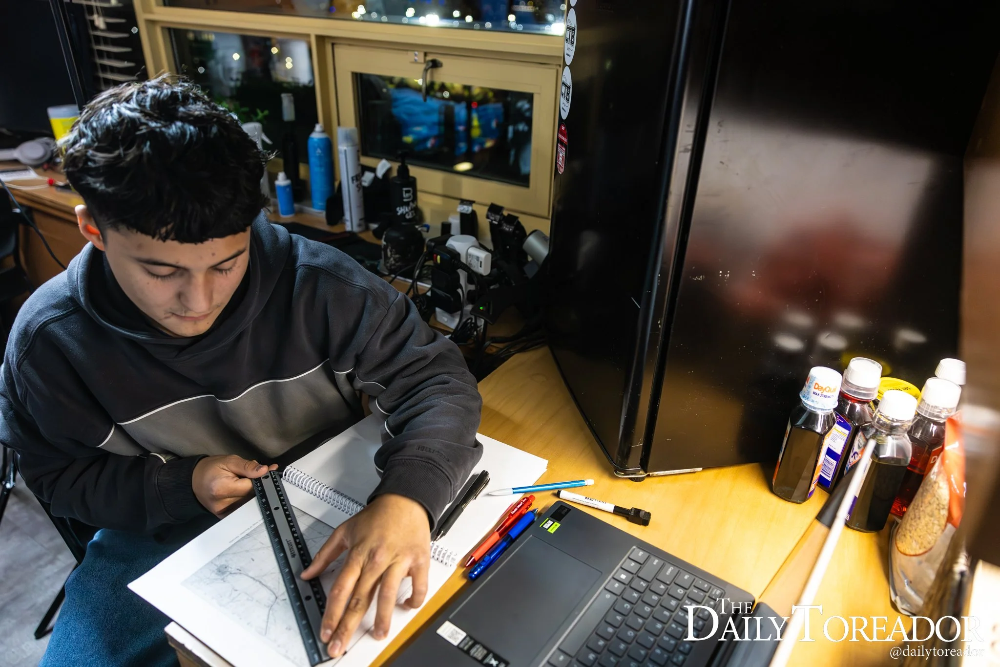 Aguirre completes his homework next to the razors and clippers of is part-time barber business.