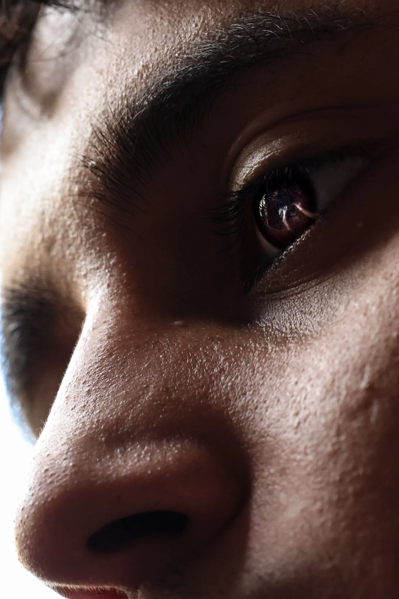 Juan Agguire, a business management major from Dallas, cuts a client as its reflected on his eyes inside of his dorm in Coleman Hall.