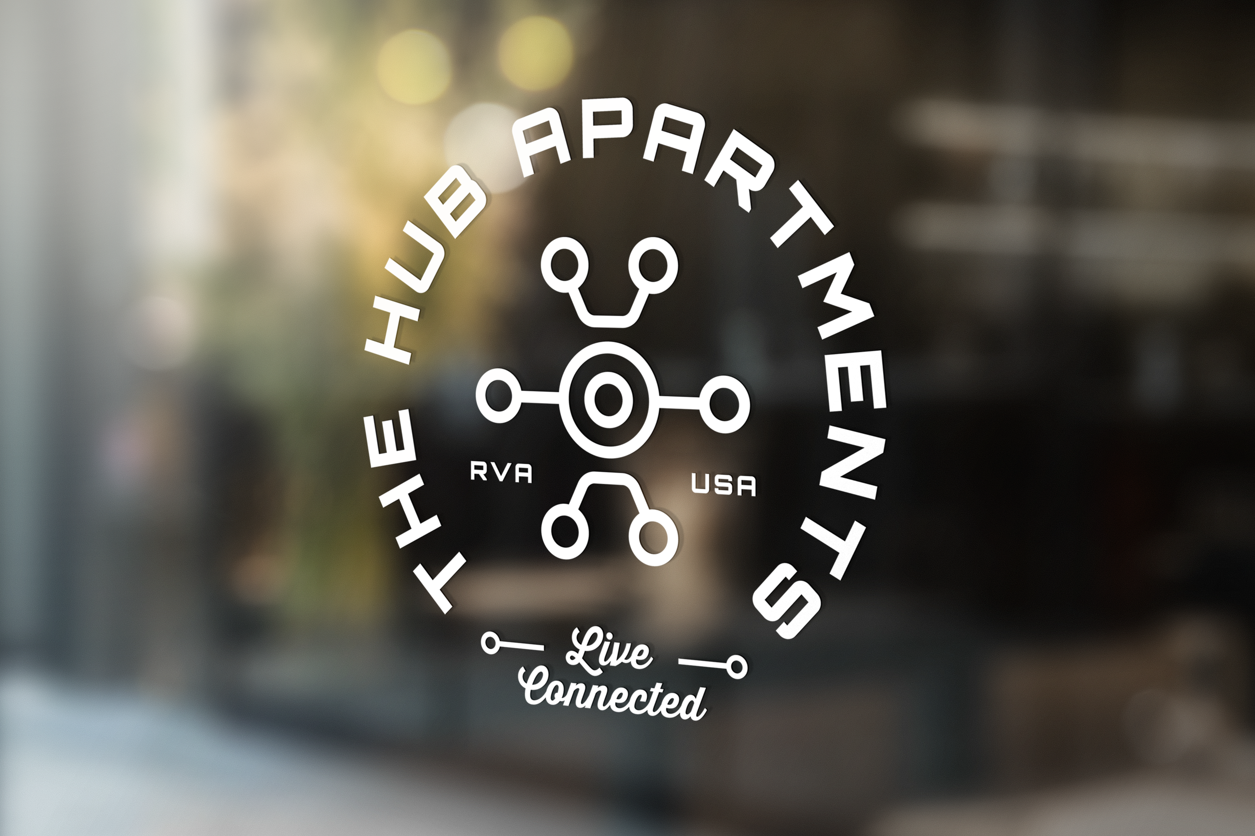 A decal on a glass window with a logo featuring a connected circle and lines design. The text around the logo reads 'The HUB Apartment Community' in an arc, with 'RVA' and 'USA' on either side of the logo. Below, the words 'Live Connected' are written.