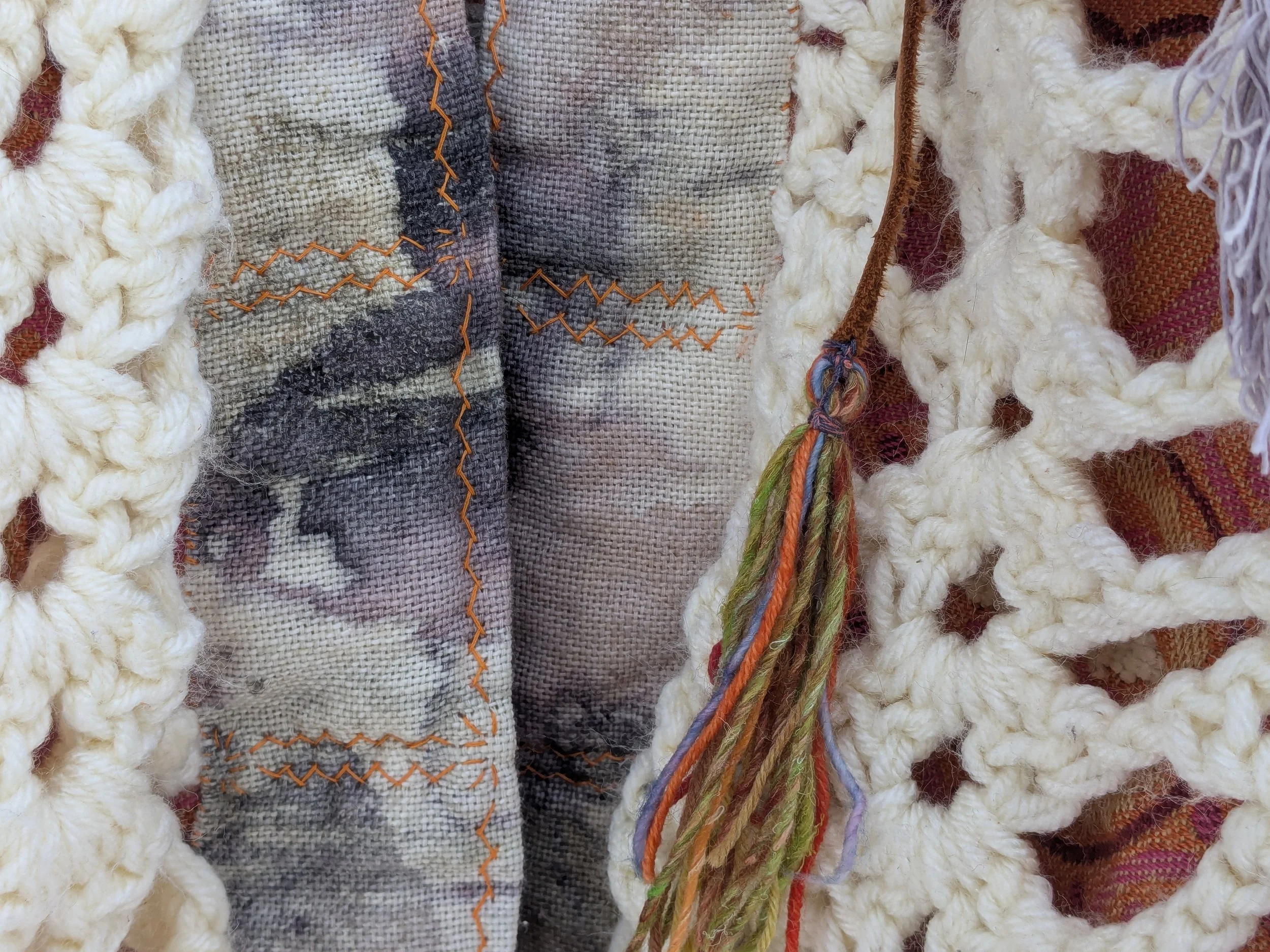 Cozy winter shawl with fully upcycled fabric, close-up of clasp tassel.