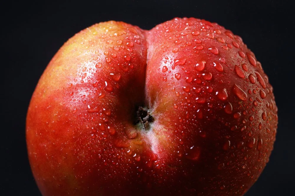 Close-up of a red apple with water droplets on its surface against a black background.