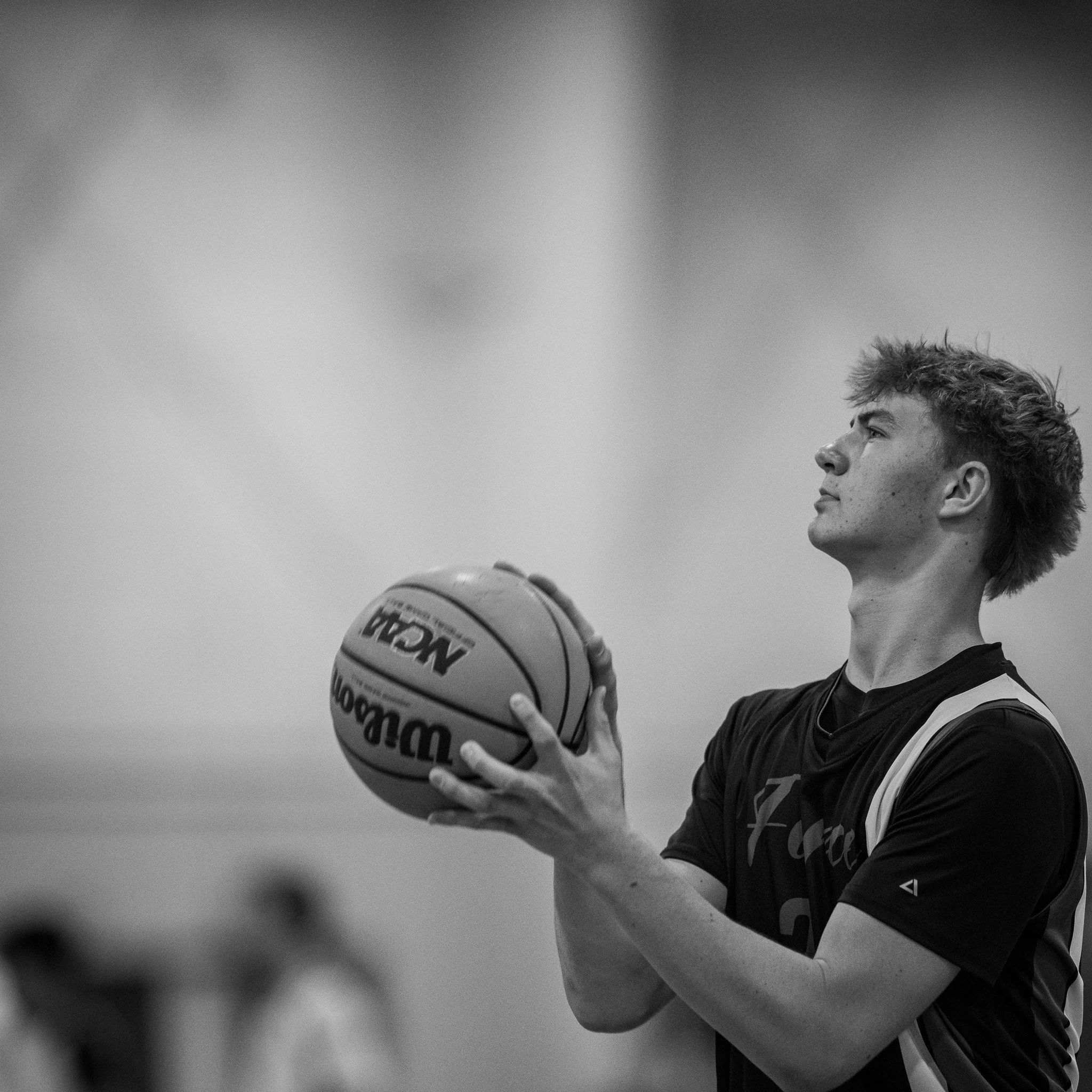 Black and white photo of a male basketball player preparing to shoot a basketball.