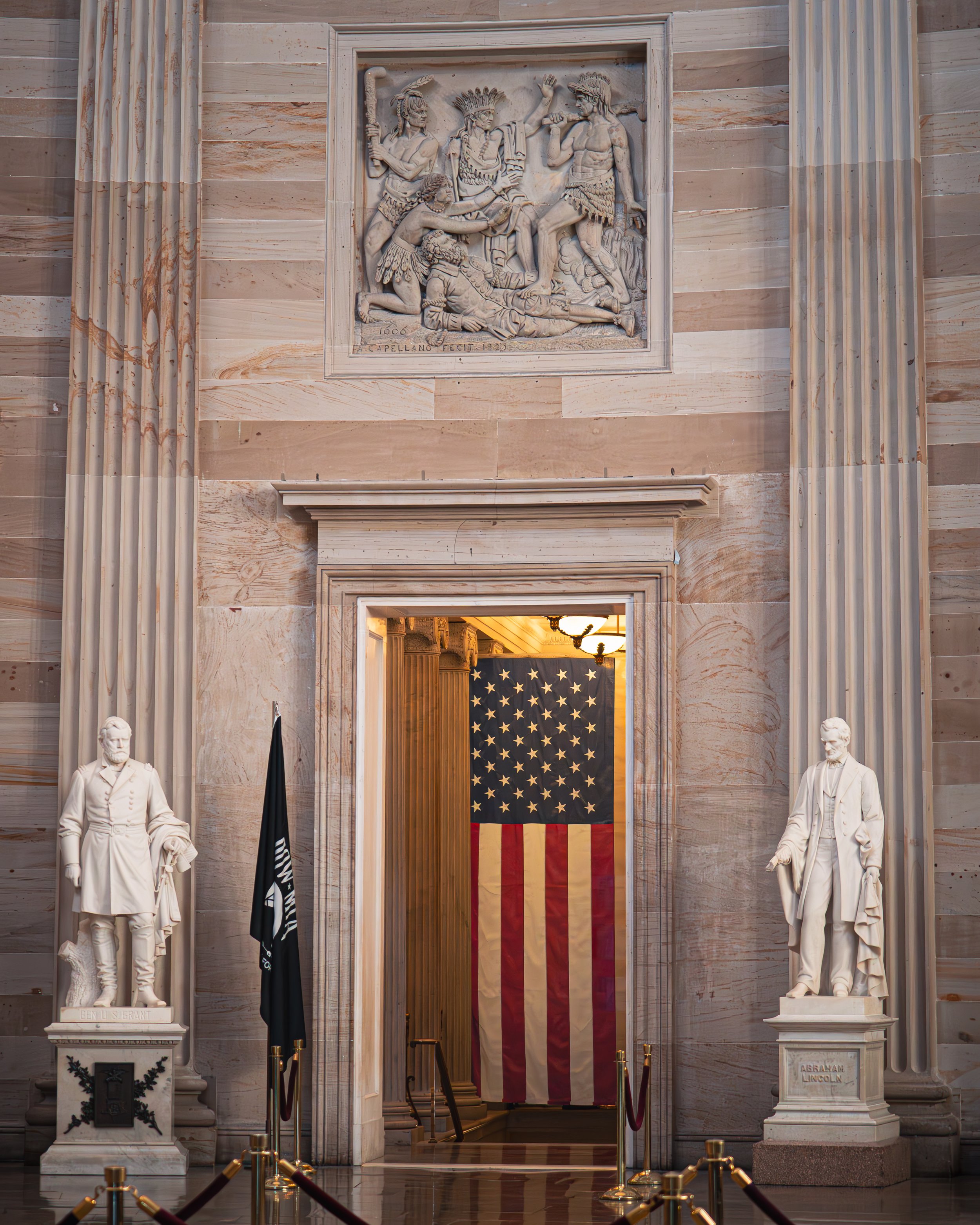 Innenraum des Kapitols mit Statuen von Benjamin Harrison und Abraham Lincoln, US-Flagge im Hintergrund, Wandrelief oben