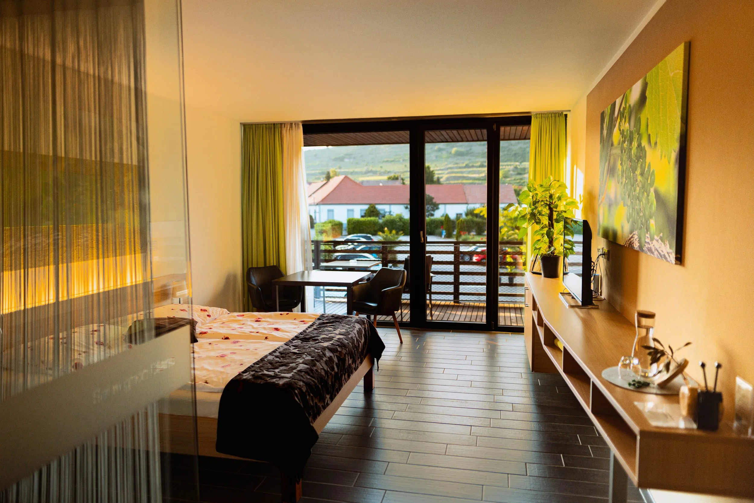 Ein modernes Hotelzimmer mit Blick auf einen Balkon und eine ländliche Umgebung im Hintergrund.