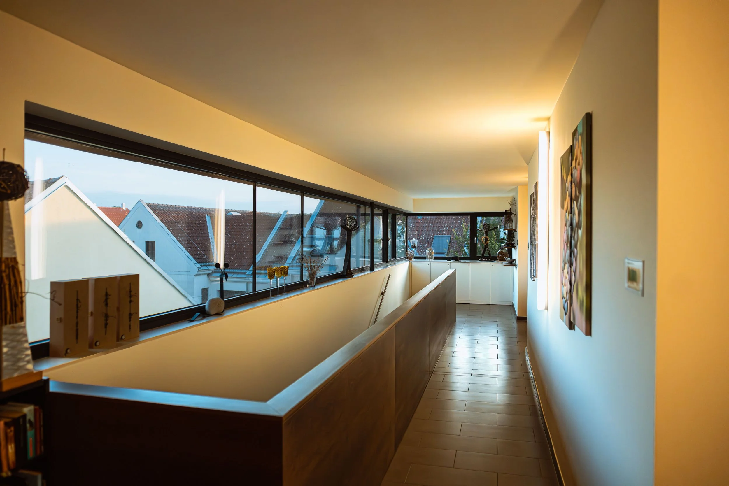 Innenansicht einer modernen, hell erleuchteten Wohnung mit großen Fenstern, Spazierhintergrund und dekorativen Kunstwerken an der Wand.