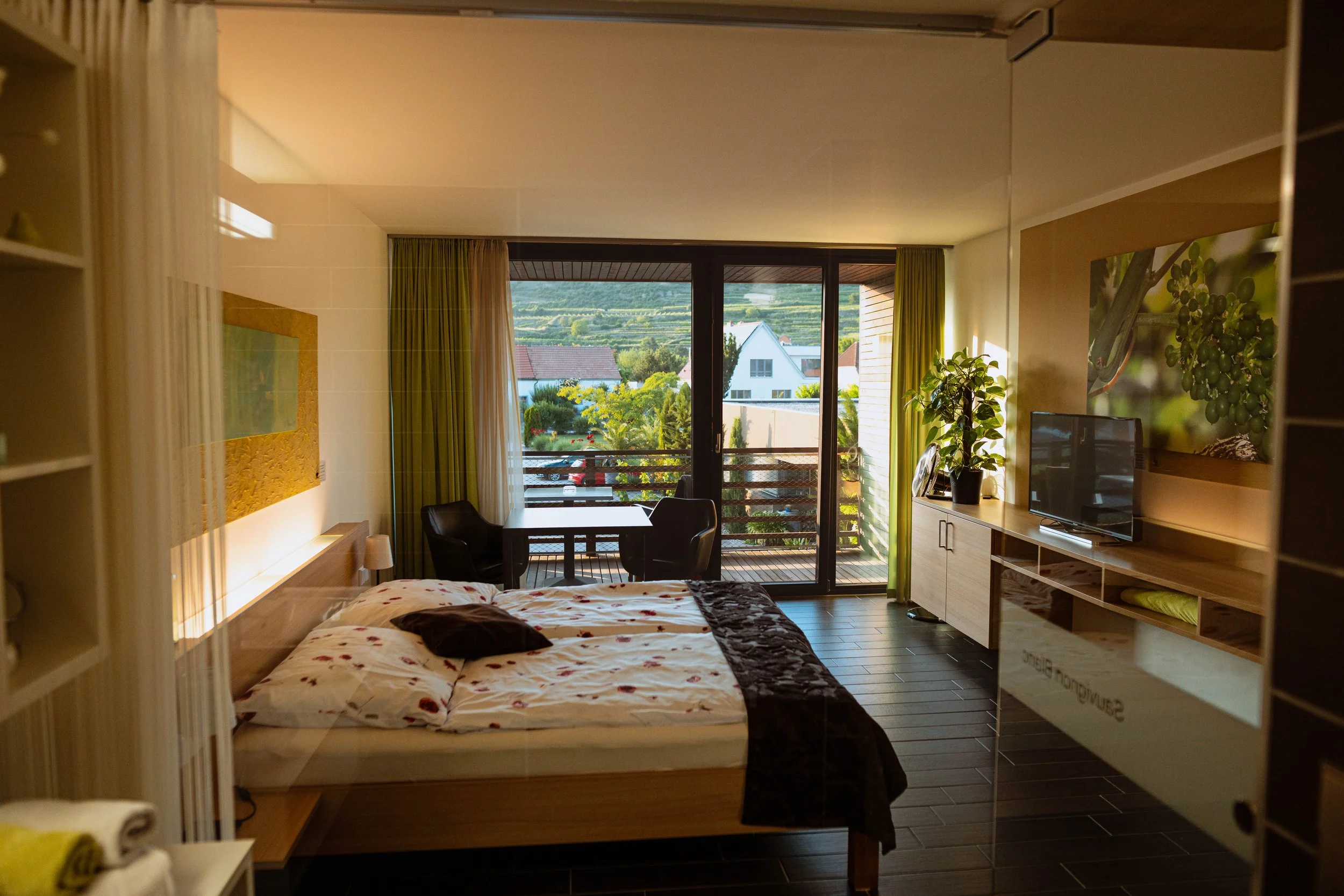 Bild eines Hotelzimmer mit Doppelbett, Fernseher, Balkon und Bergen im Hintergrund.