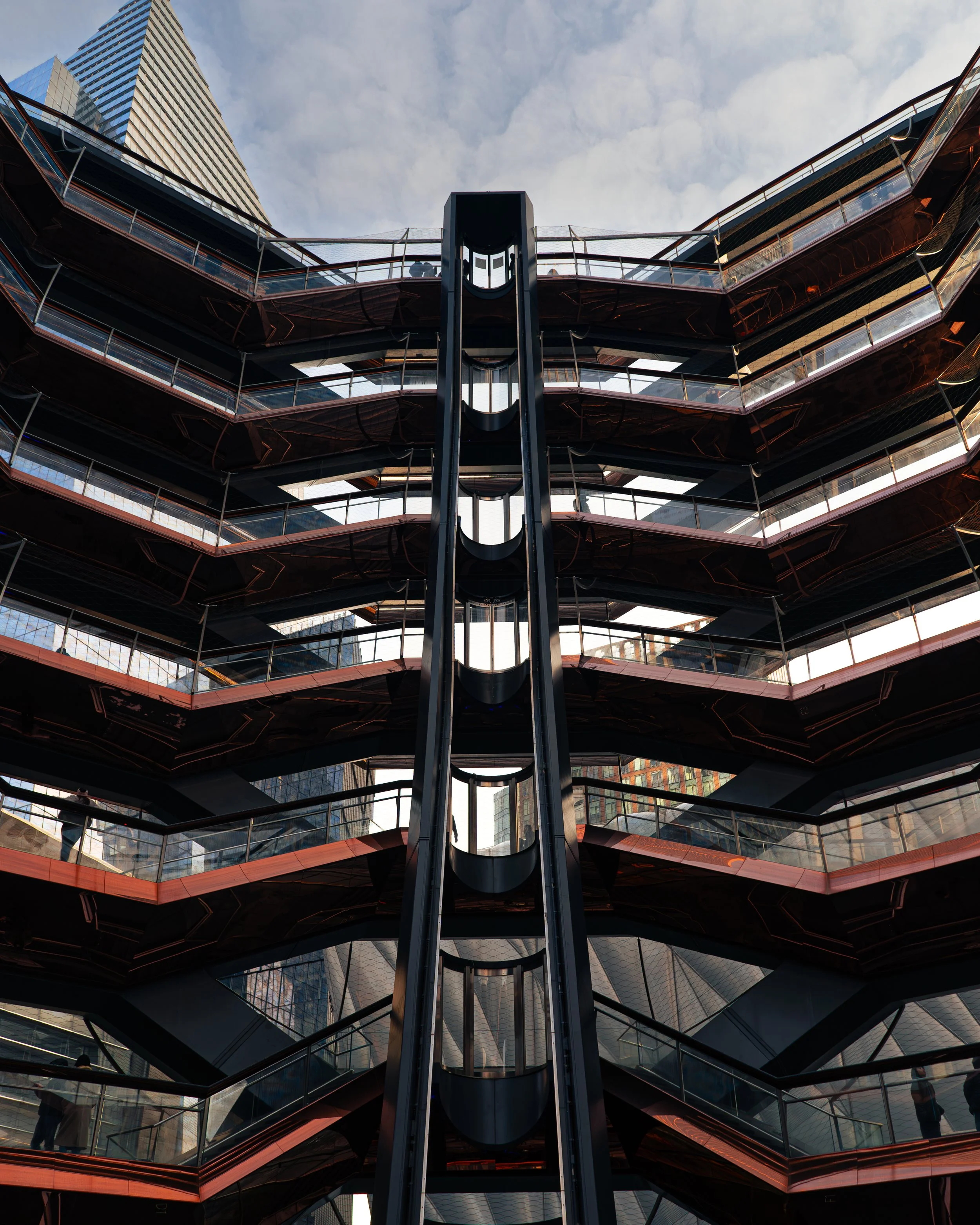 Mehrstöckiges Modernes Parkhaus mit schrägen Rampen und reflektierenden Fassaden in einer städtischen Skyline bei Tag.